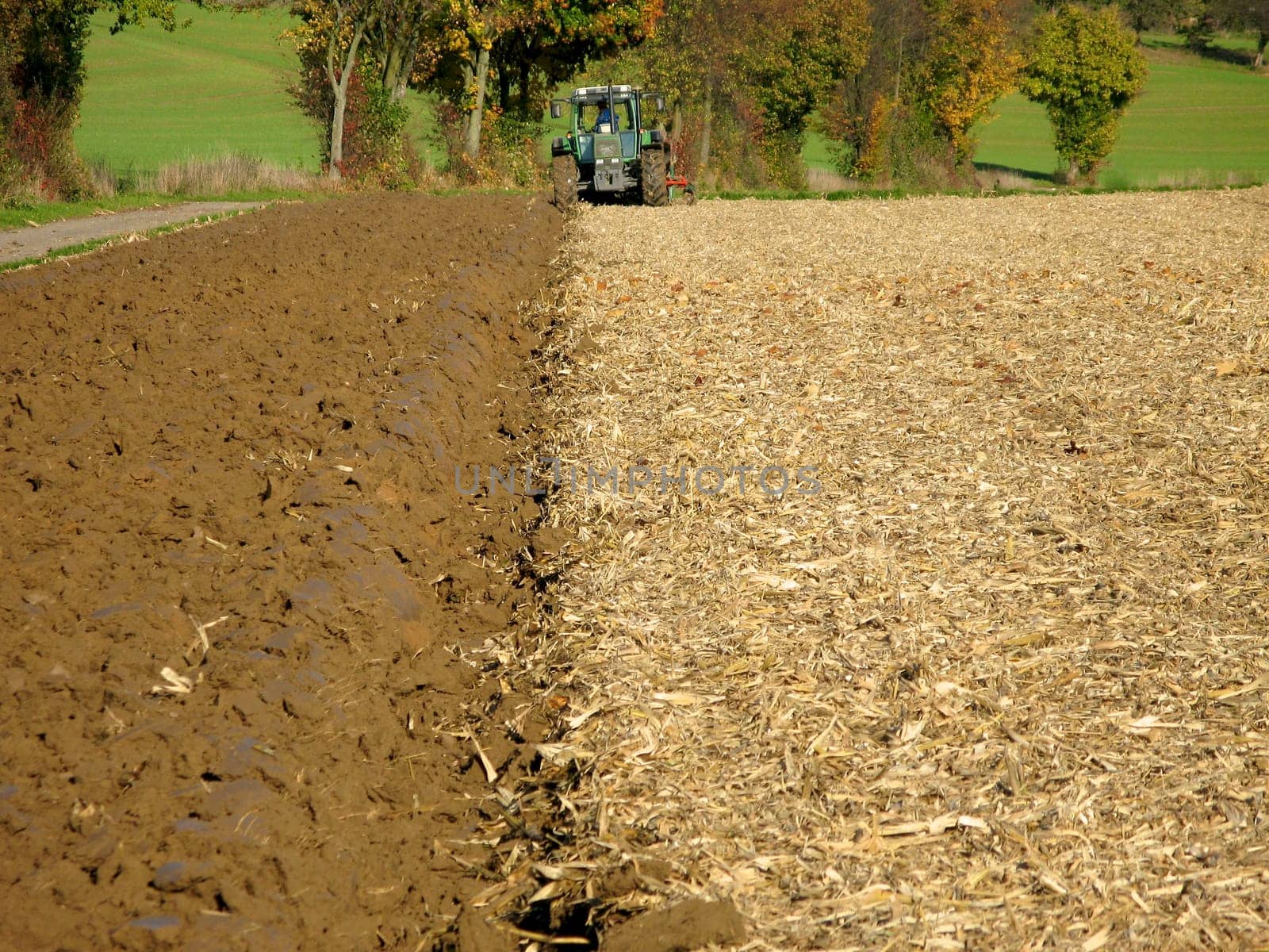 Tractor ploughs brown field in Kraichgau,Germany. Filling the format. Landscape.