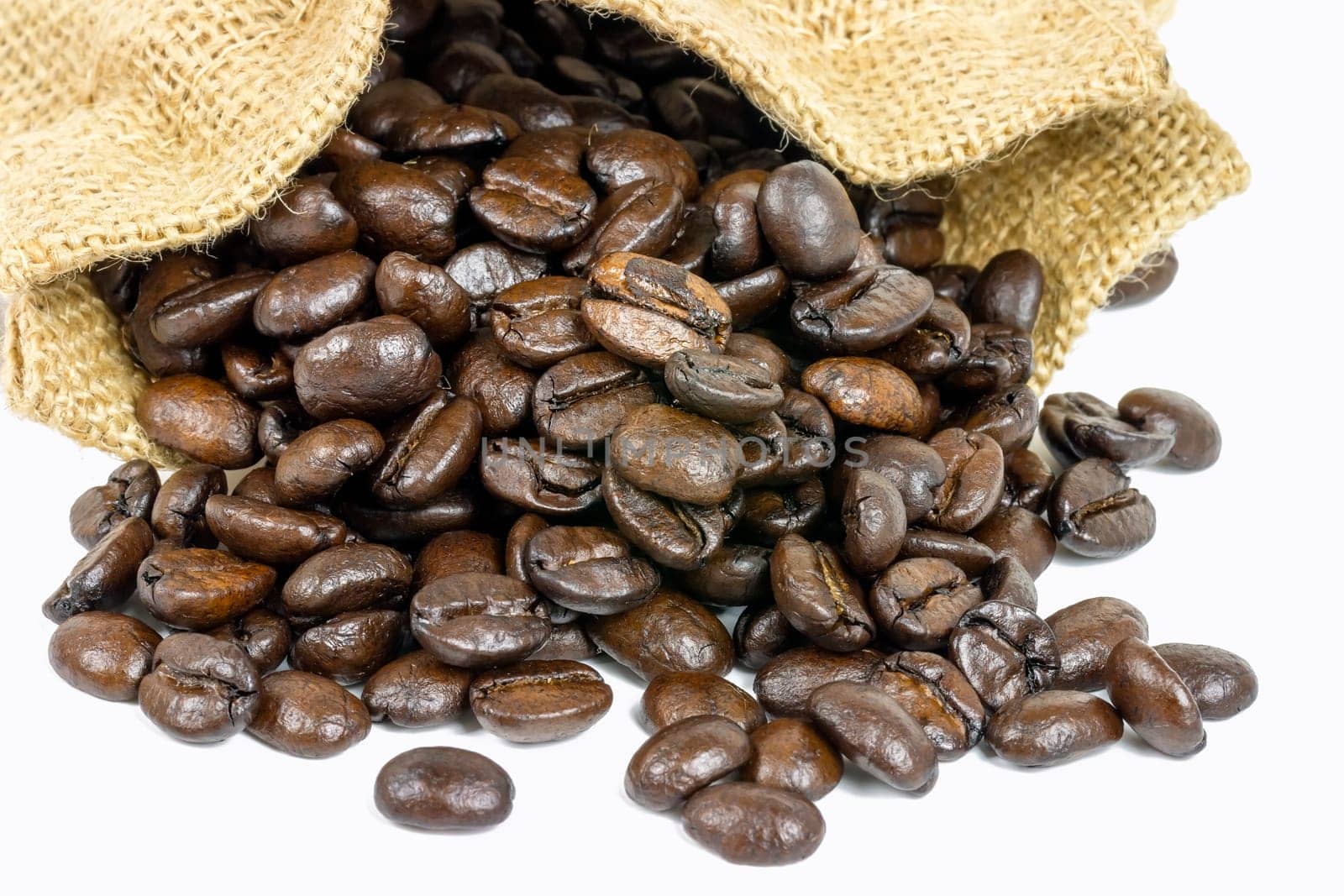 Roasted coffee beans in jute sack on white background