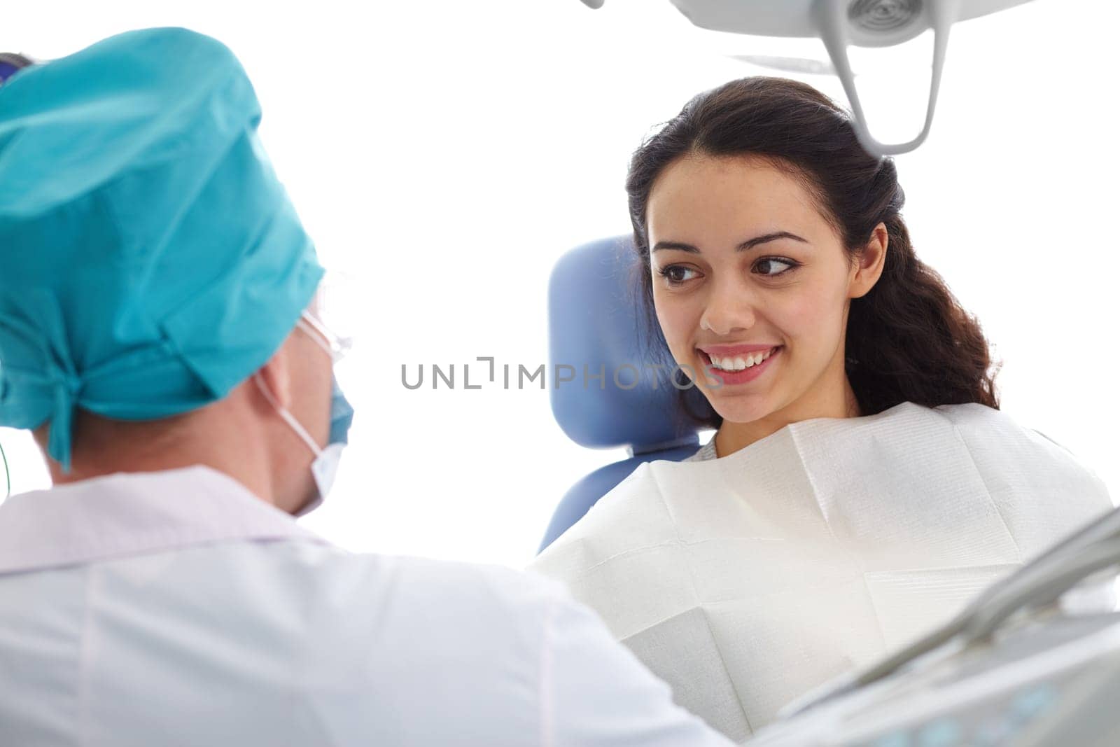 Young woman sitting in a dental chair and looking at doctor