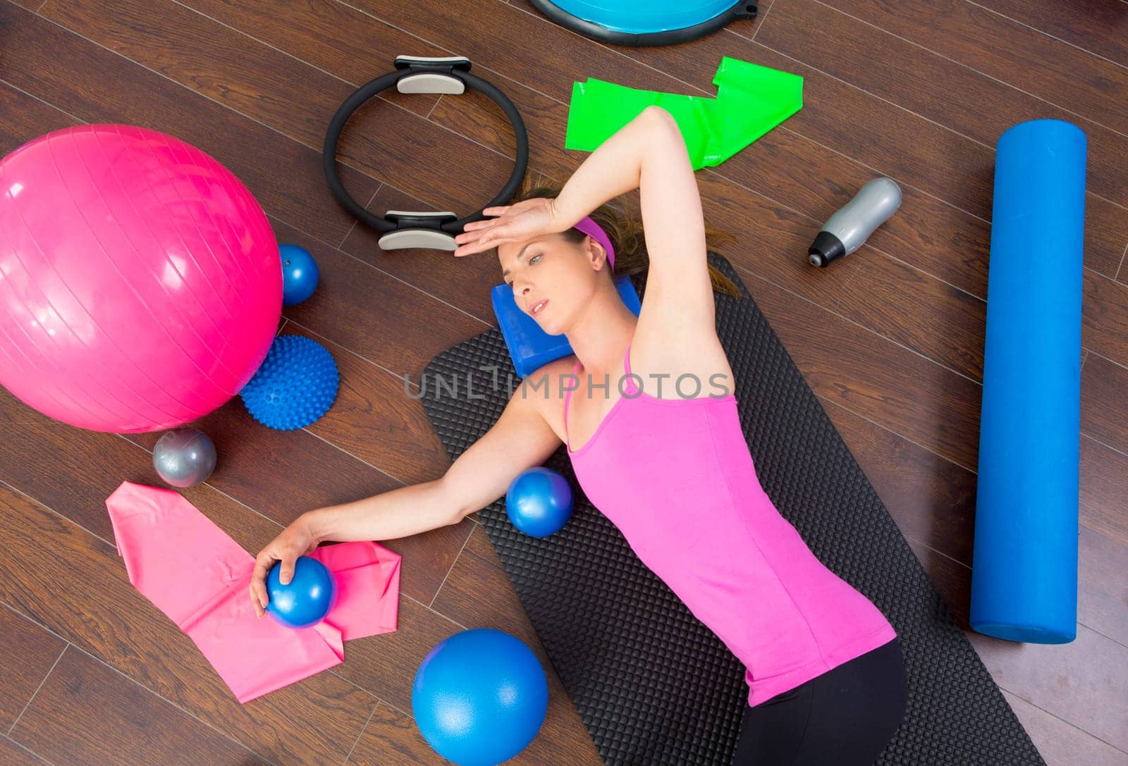 Aerobics instructor woman tired resting lying on mat with pilates balls and bands