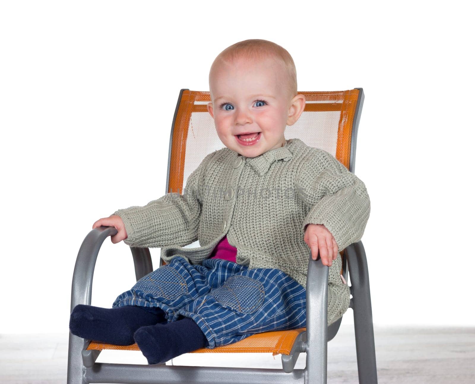 Happy smiling baby sitting alone in a stylish modern childs highchair with copyspace