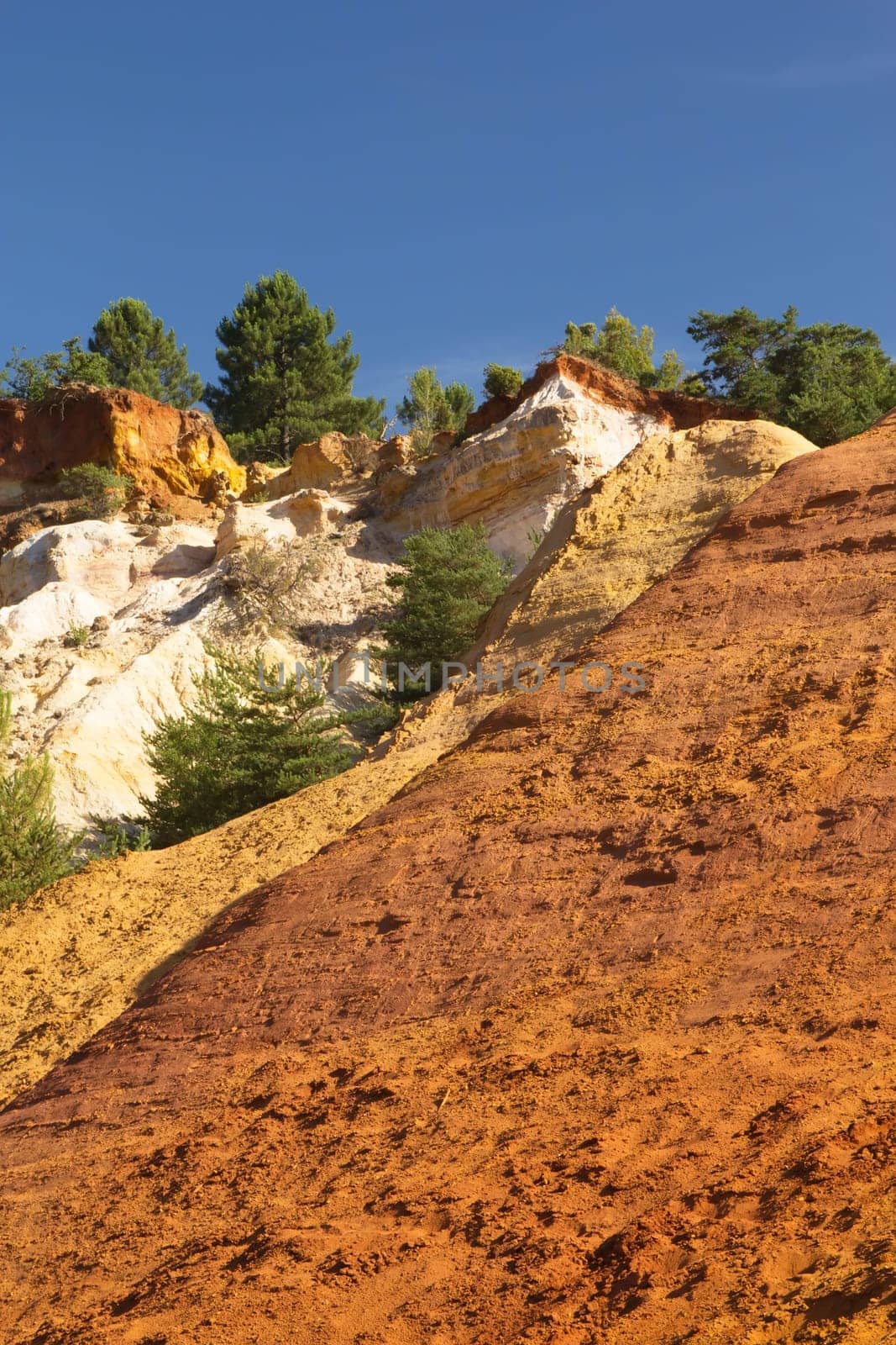 Colorful ocher hills and blue sky in the background. Ocher rocks (French Colorado) near Rustrel (Provence, Southern France)