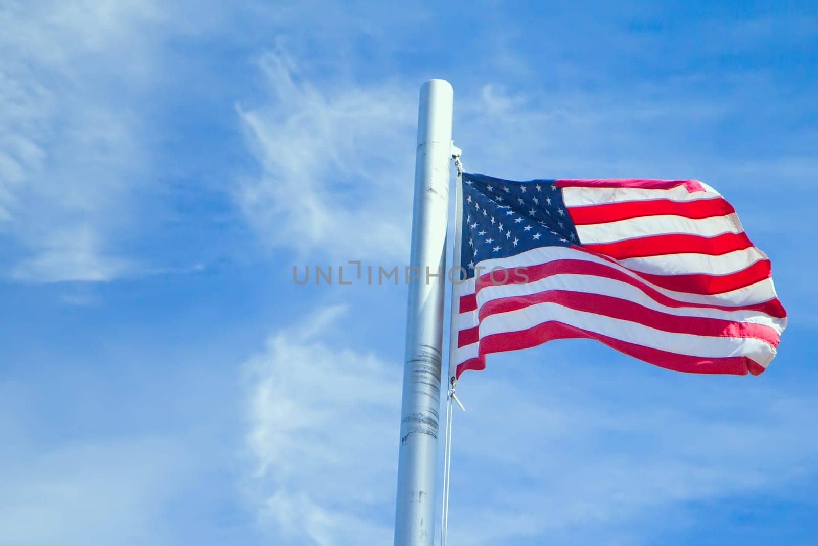 US Flag on Pole. Blue sky in the background.