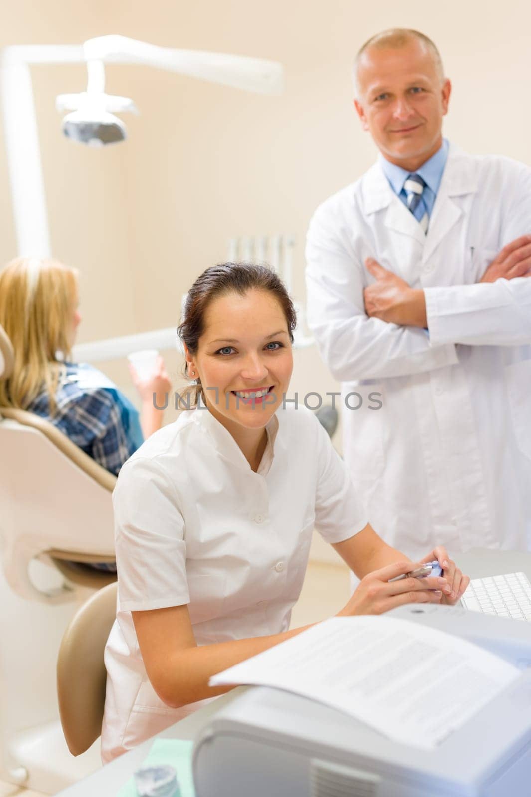 Dentist with assistant smiling at stomatology office professional health care