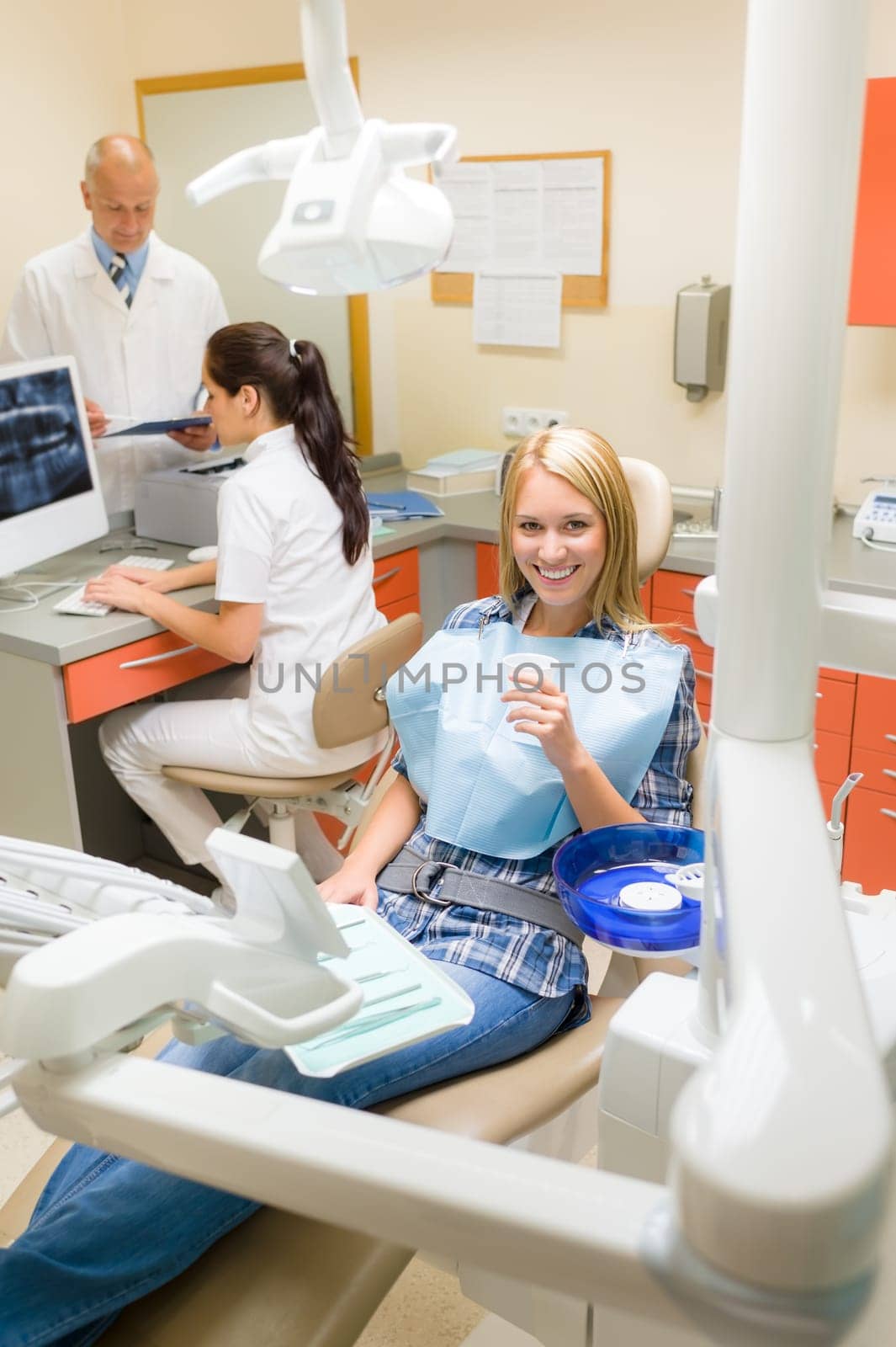 Happy female patient at dental surgery dentist with assistant