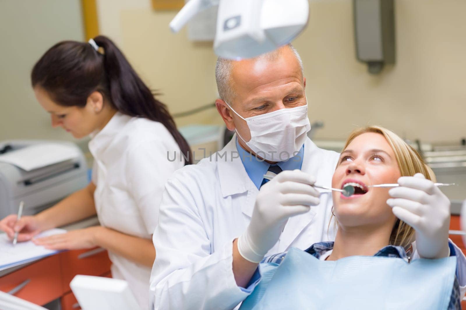 Professional dentist doing teeth checkup on female patient dental surgery