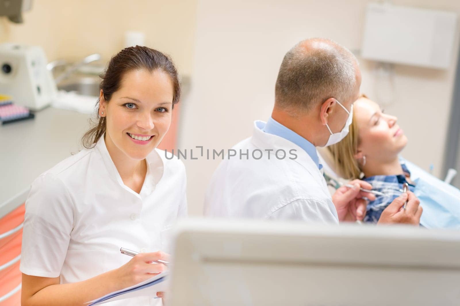 Smiling dental nurse prepare patient documentation stomatology clinic