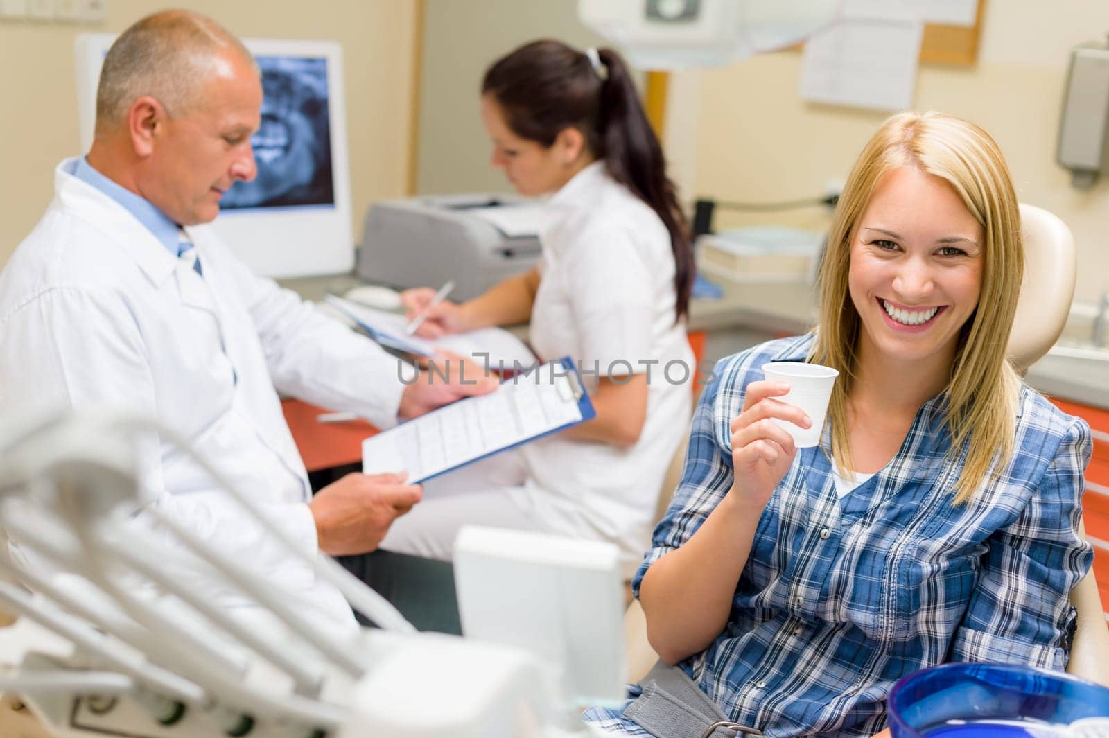 Woman beautiful smile at dental surgery male dentist check documents