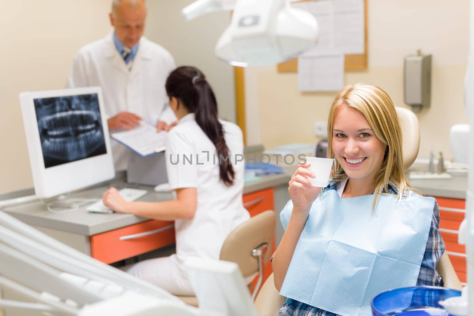 Dental surgery smiling female patient dentist consulting with assistant nurse