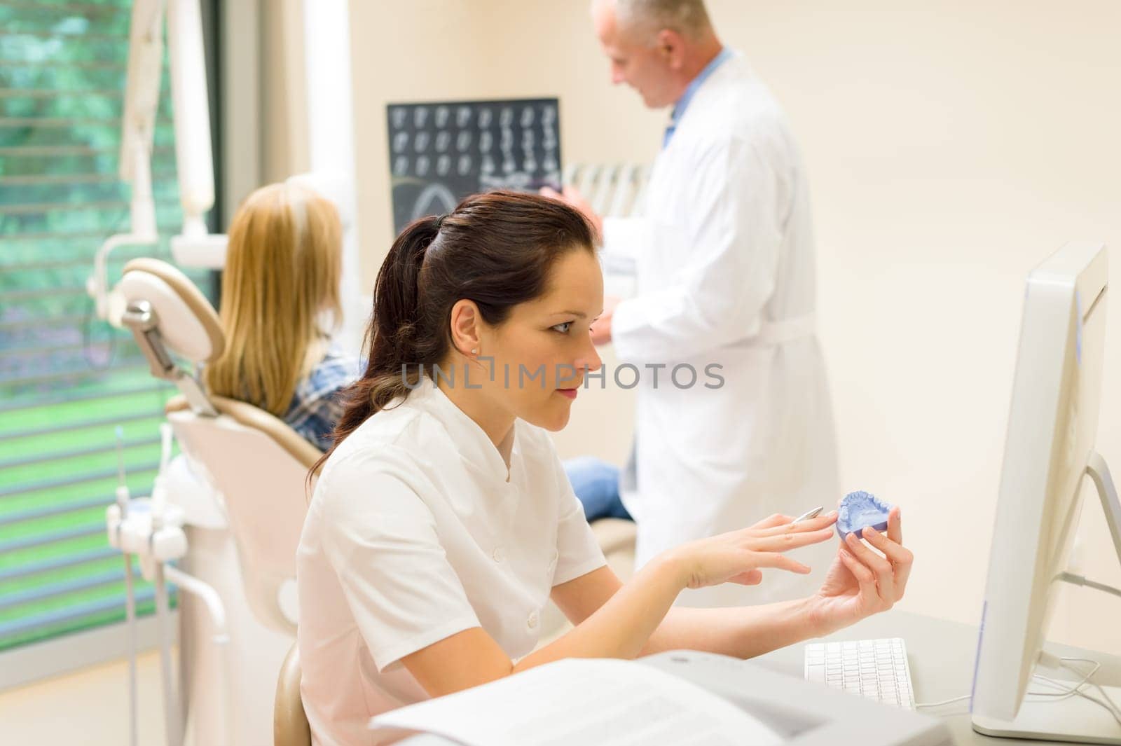 Dental surgery nurse hold print of teeth dentist with patient