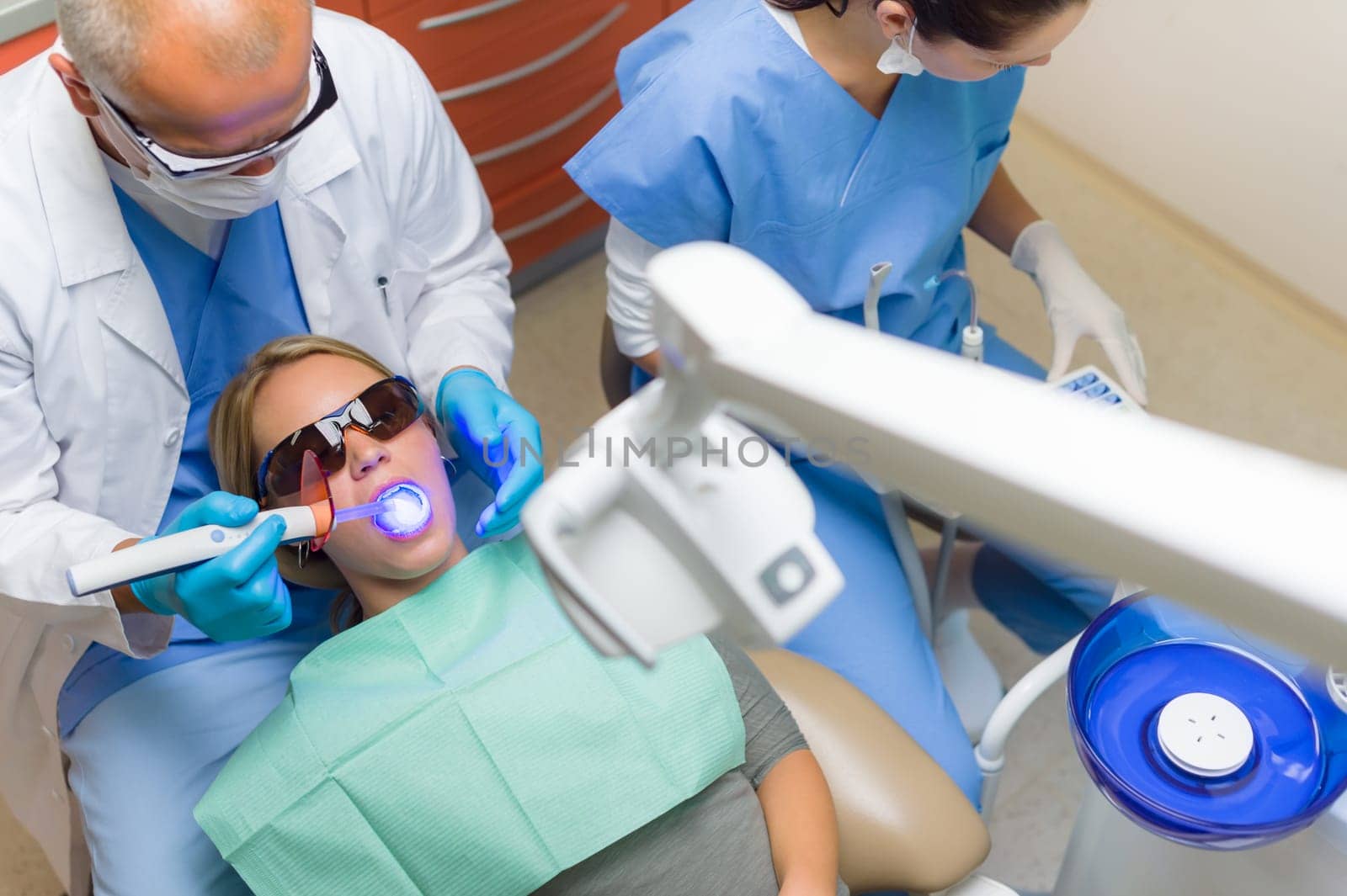 Young woman patient have dental surgery dentist use UV lamp