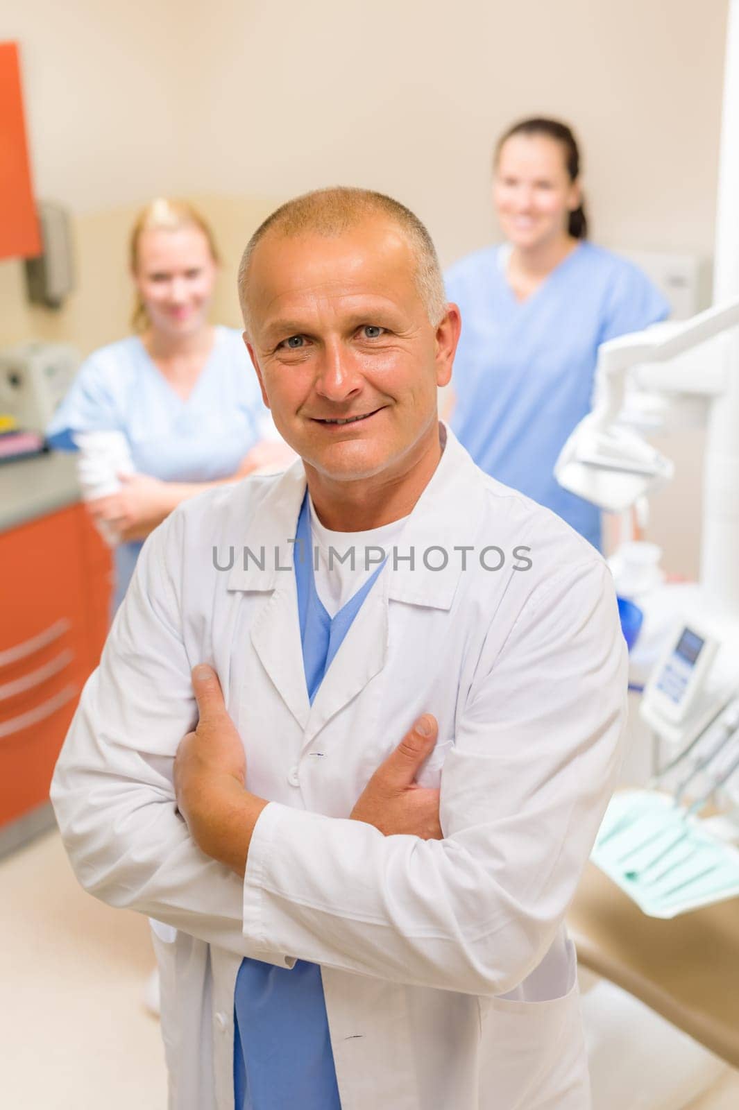 Portrait of mature dentist man with team in stomatology clinic