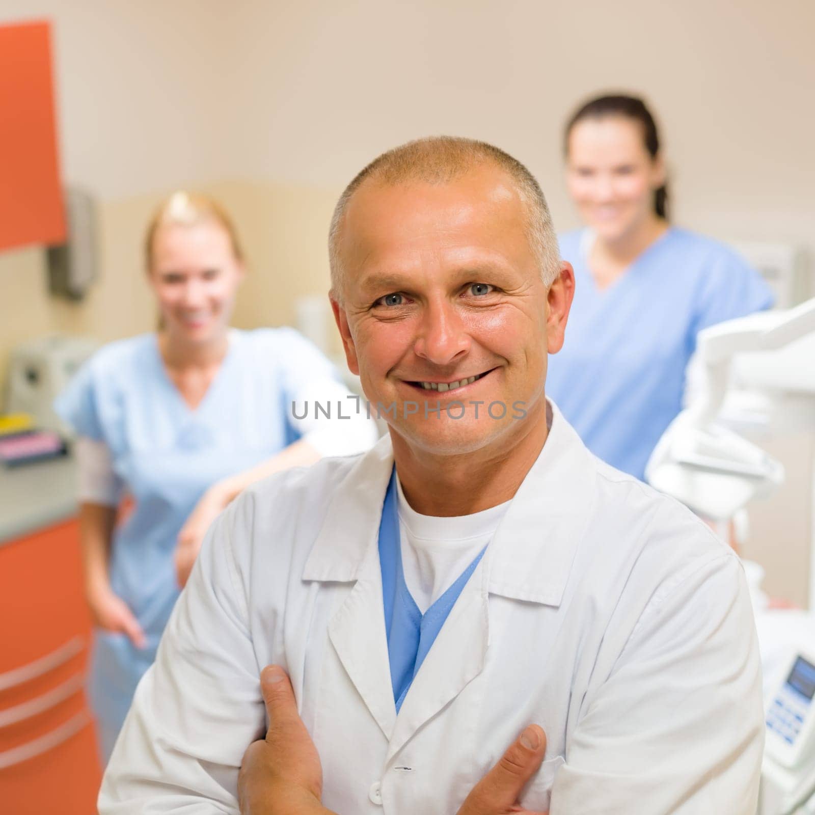 Smiling male dentist posing with female assistants at office