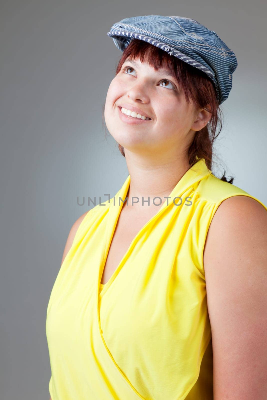 Portrait of a happy girl in yellow blouse and a denim cap