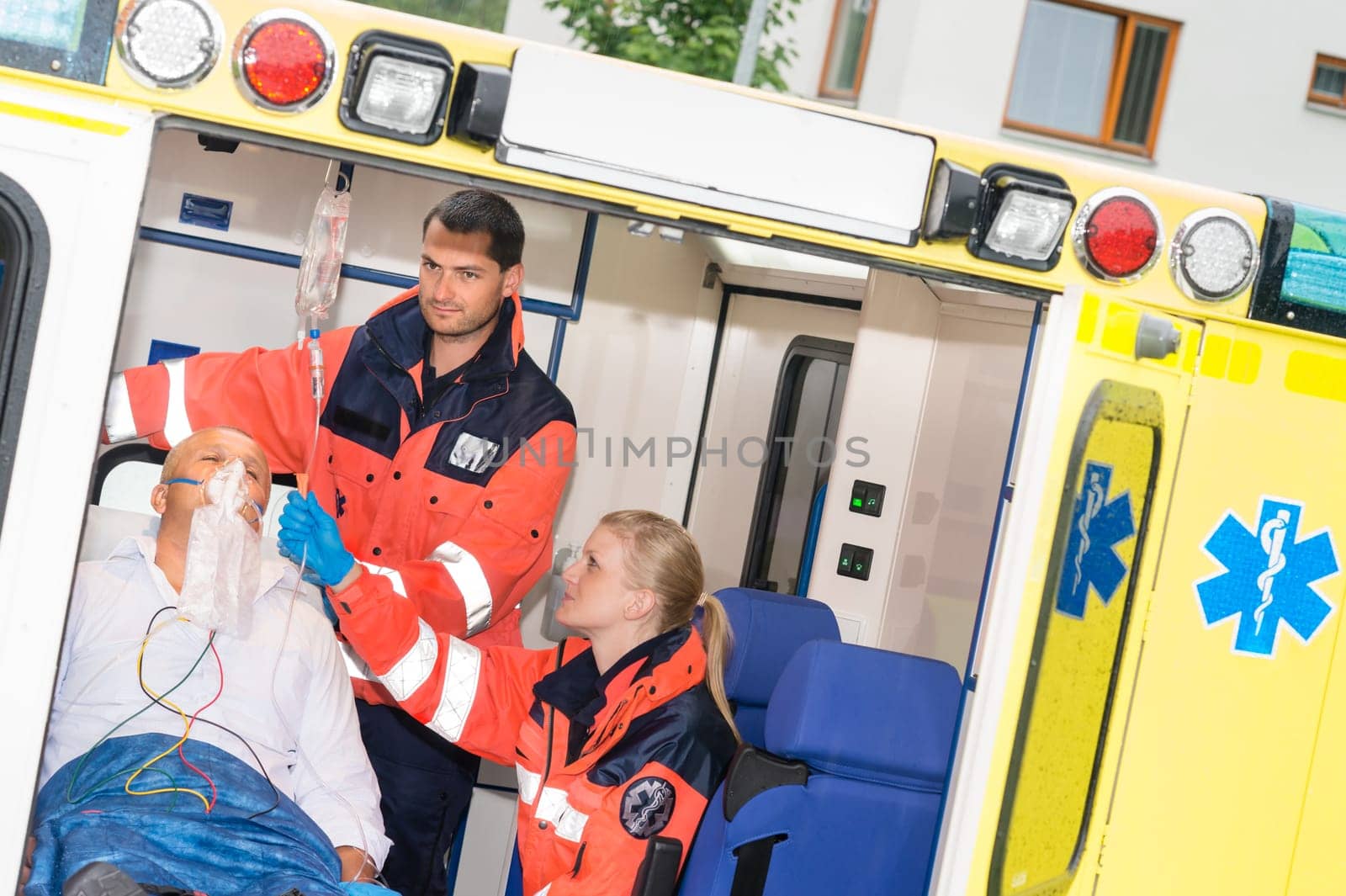 Paramedics checking IV drip patient in ambulance treatment aid emergency