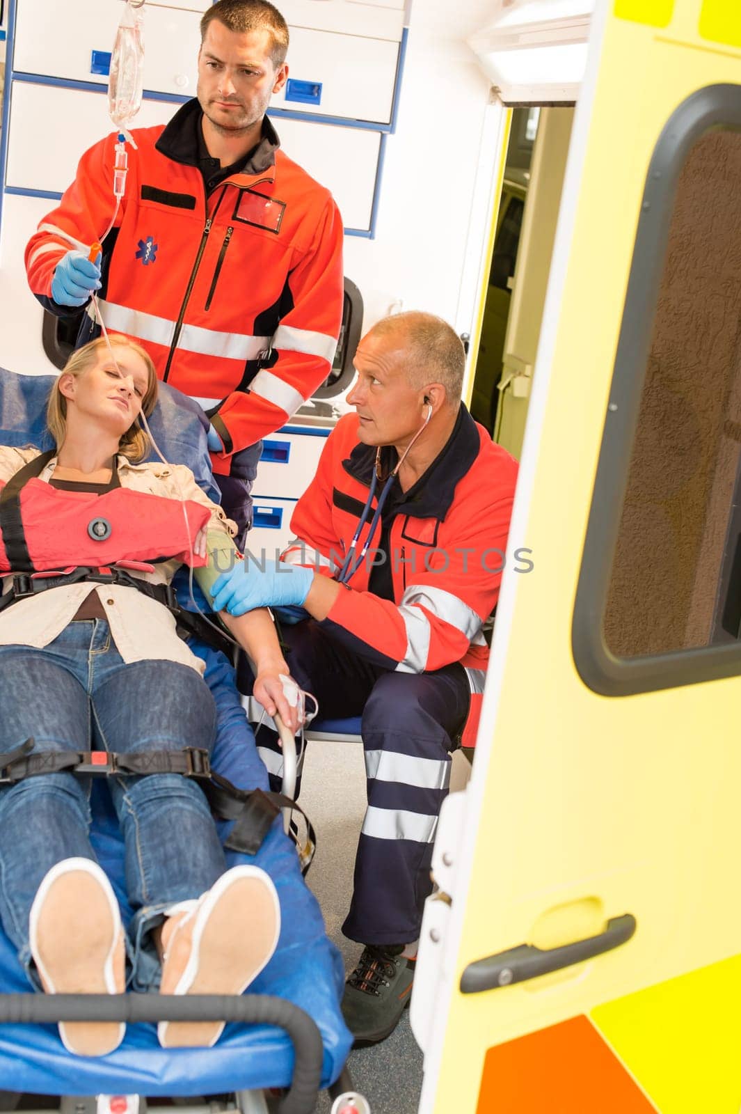 Paramedics help unconscious woman emergency ambulance measure blood pressure