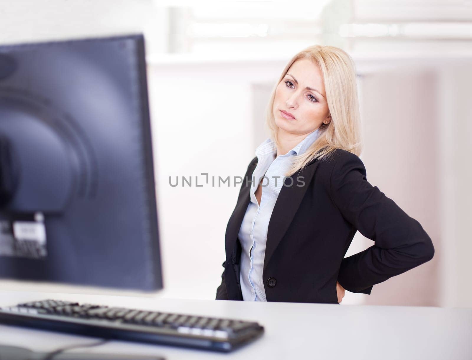 Business women having back pain at computer workplace