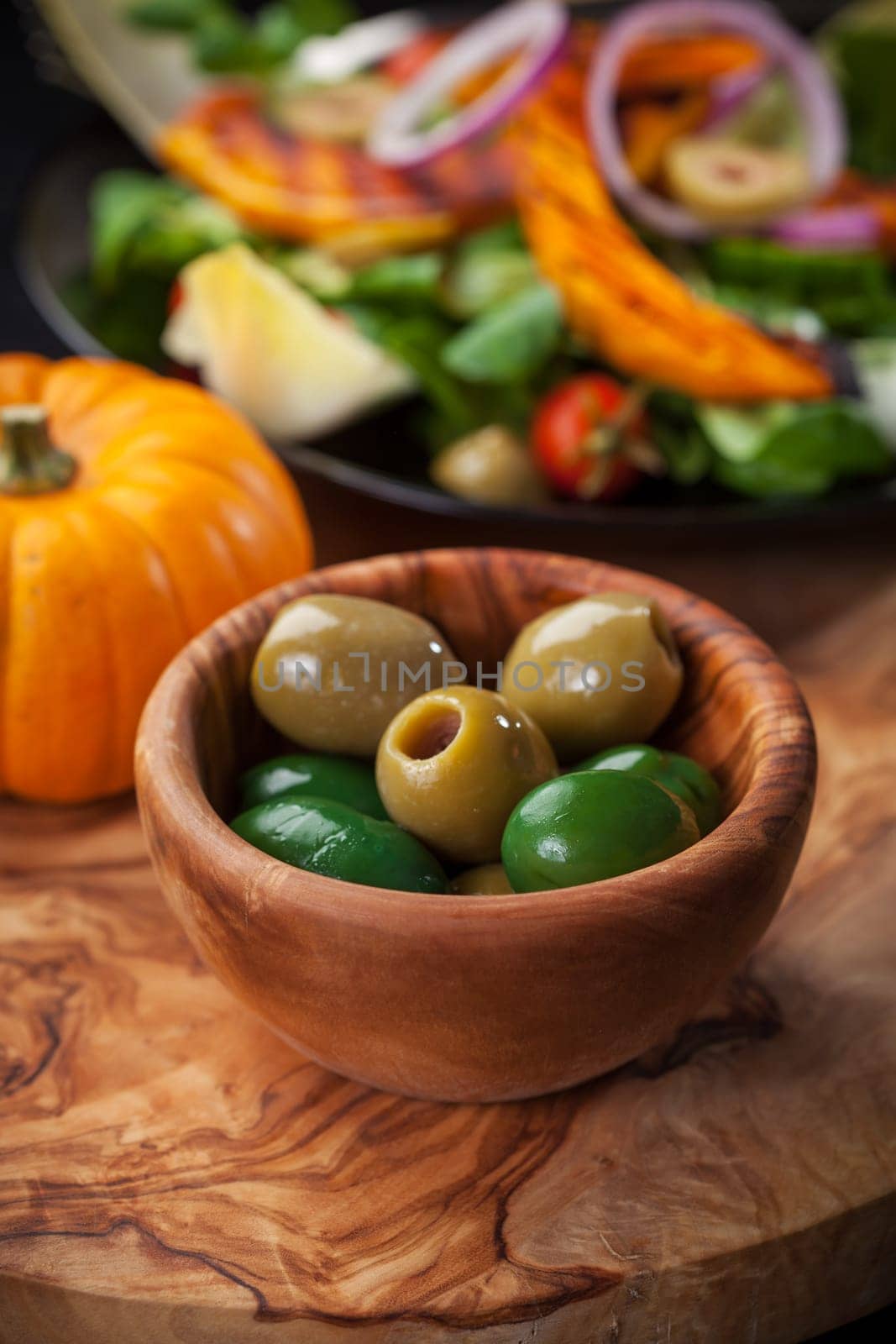 Delicious green olives in the bowl with salad