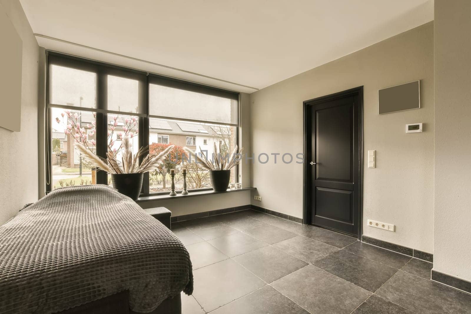 a hotel room with a bed and two large windows looking out onto the street in the photo is taken from inside