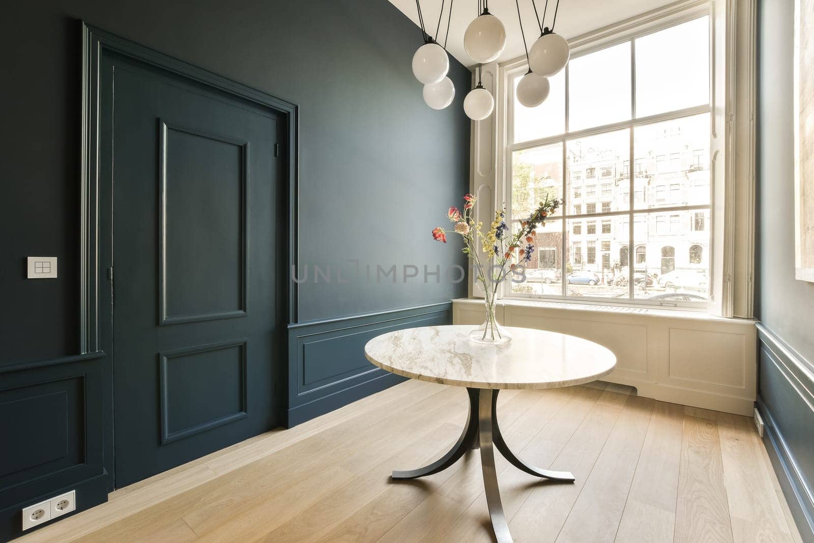 a room with dark blue walls and white trim on the walls, there is a small round table with flowers in it