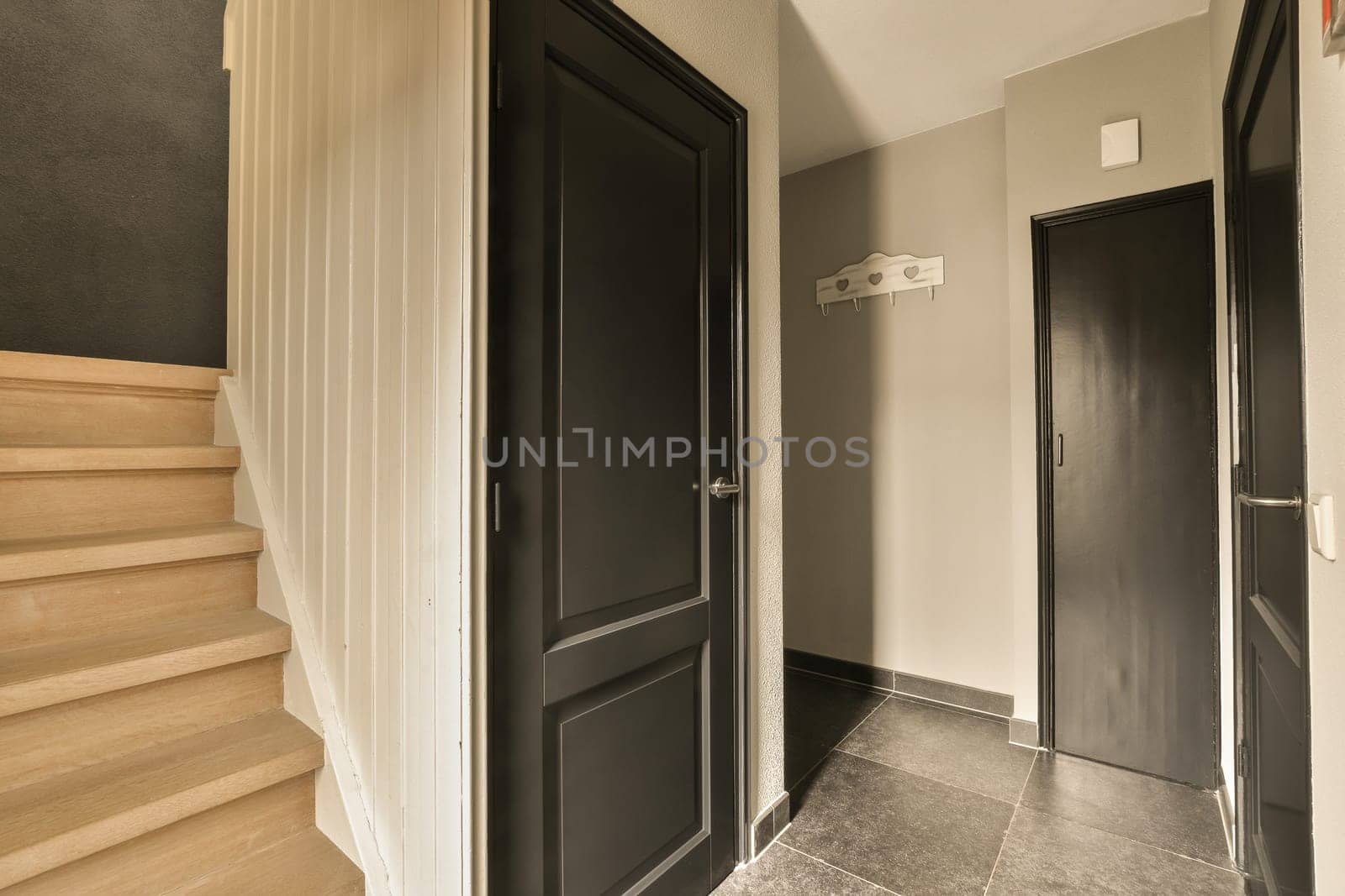 a hallway with black doors and wooden steps leading up to the second floor in an apartment or condo, which is for sale