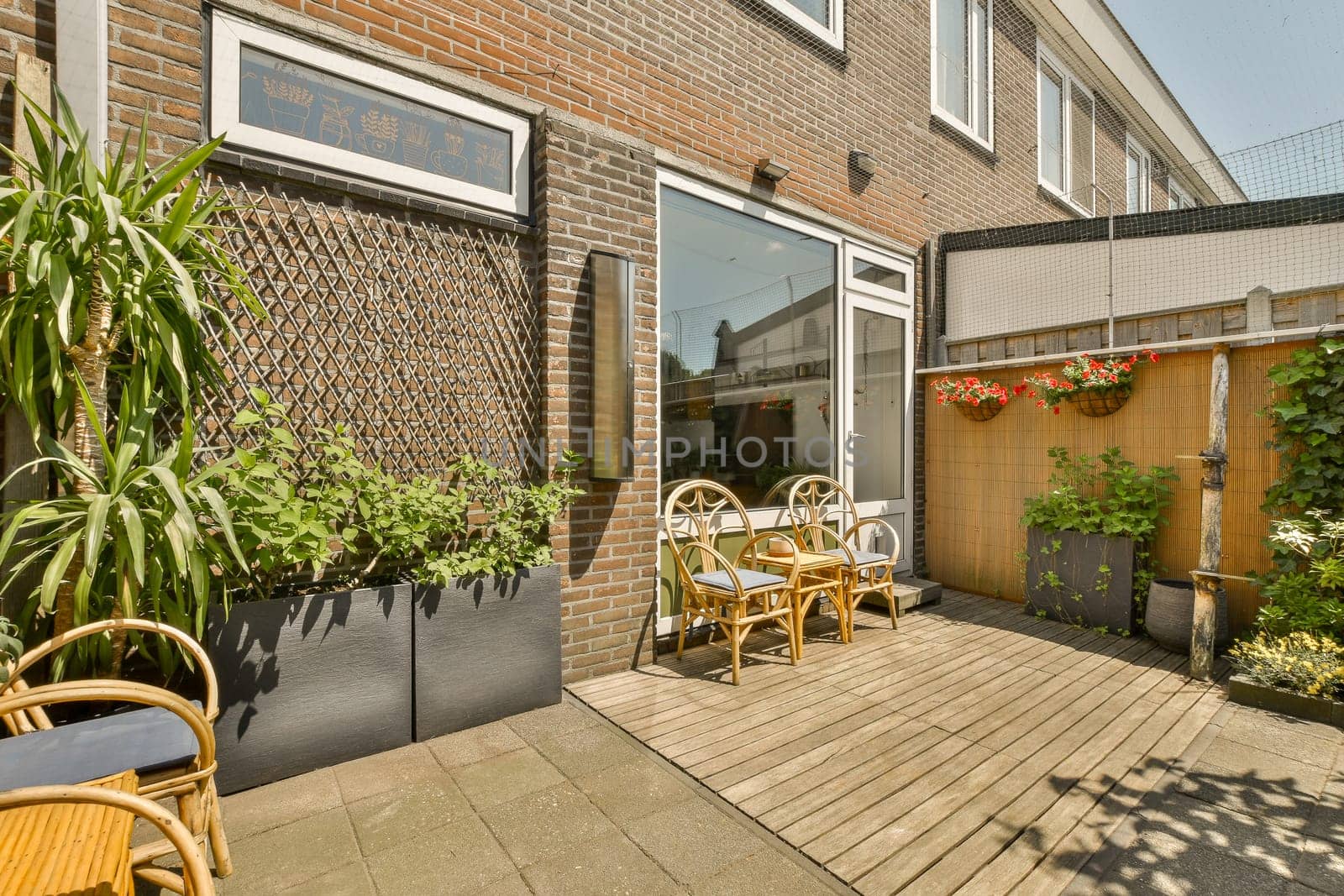 a patio with chairs and plants on the decking area in front of a brick wall that has been painted white