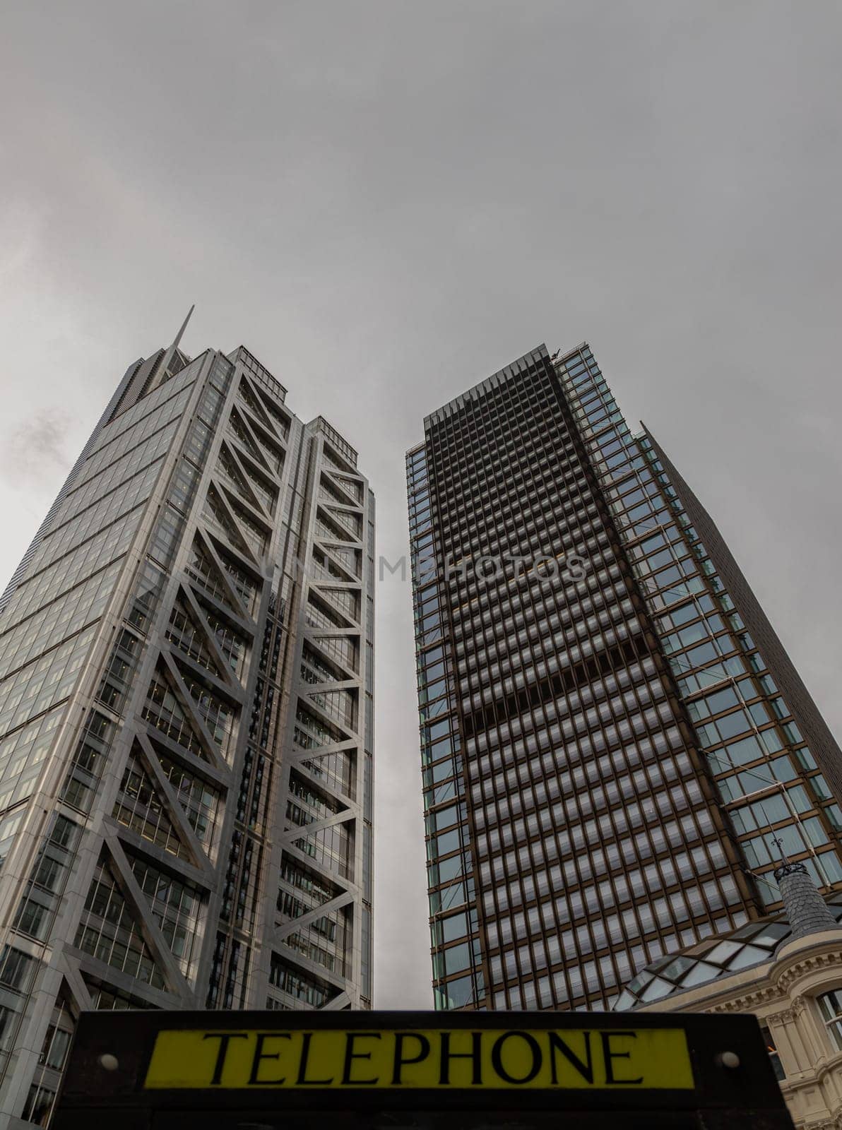 London, UK - Oct 23, 2023 - Looking Up of Public telephone sign in front of skyscraper. View of Liverpool street modern office buildings which major London financial district main, London shining buildings, Architectural exterior view, Space for text, Selective focus.