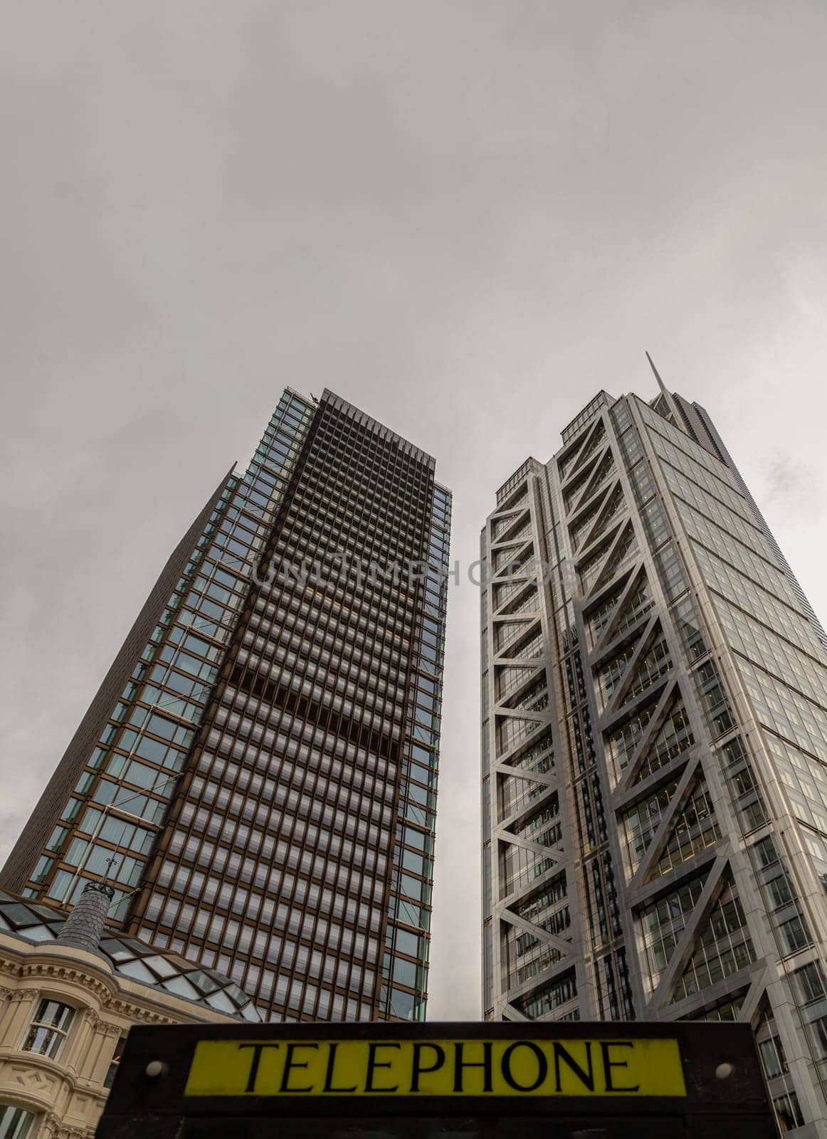 London, UK - Oct 23, 2023 - Looking Up of Public telephone sign in front of skyscraper. View of Liverpool street modern office buildings which major London financial district main, London shining buildings, Architectural exterior view, Space for text, Selective focus.