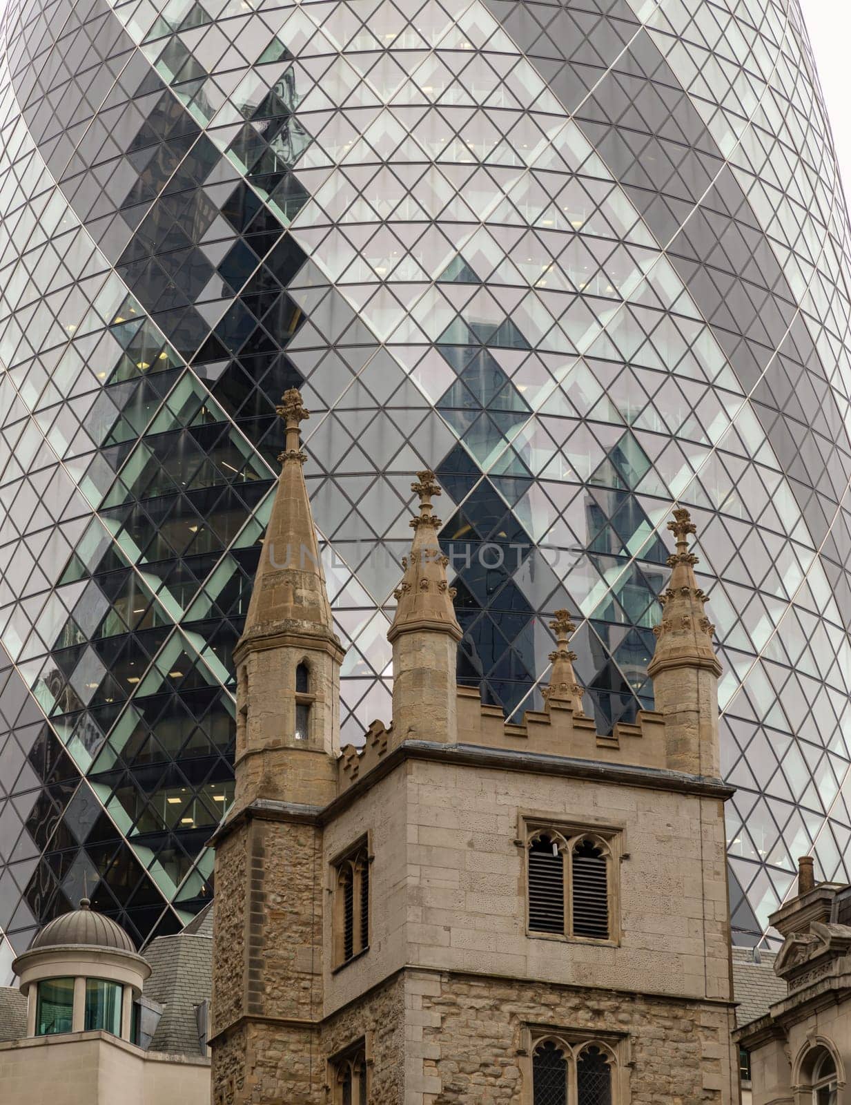 London, UK - Oct 23, 2023 - Tower of St Andrew Undershaft Church in front of The Gherkin office building background. Architectural view of old and new buildings in contrasting classical and modern designs, Space for text, Selective focus.