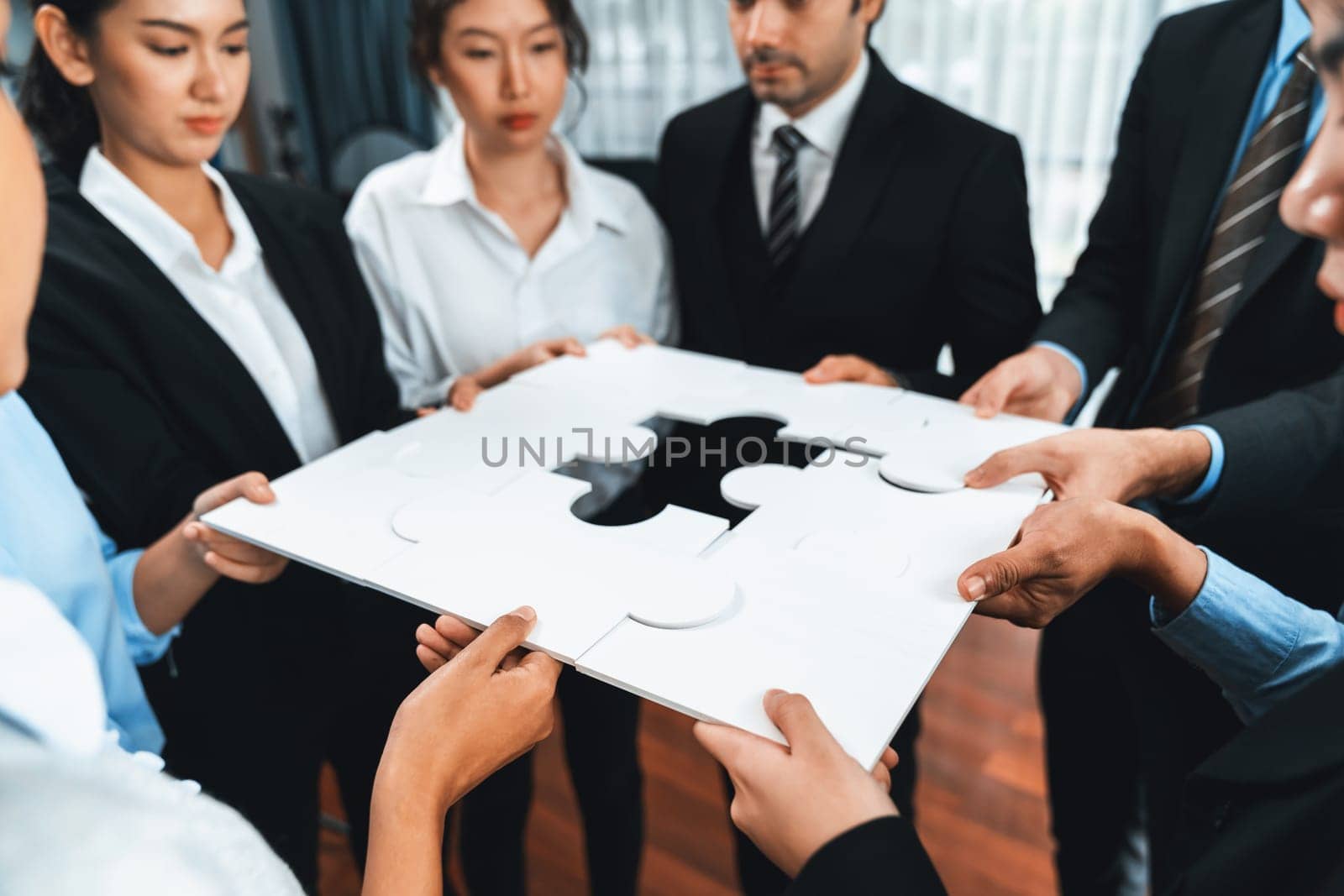 Multiethnic business people holding jigsaw pieces and merge them together as effective solution solving teamwork, shared vision and common goal combining diverse talent. Meticulous