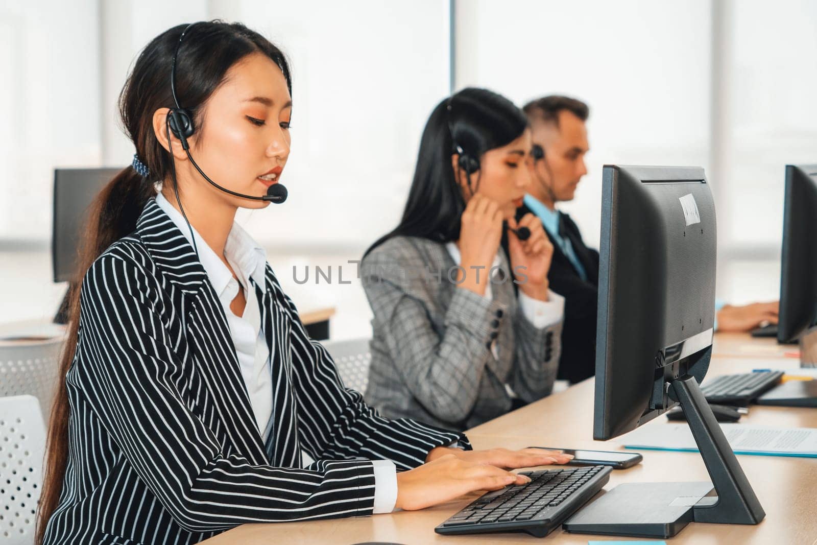 Business people wearing headset working in office to support remote customer or colleague. Call center, telemarketing, customer support agent provide service on telephone video conference call. Jivy