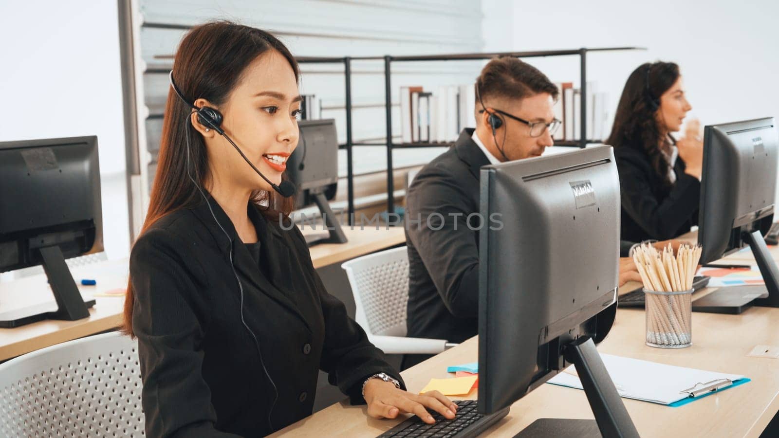 Business people wearing headset working in office to support remote customer or colleague. Call center, telemarketing, customer support agent provide service on telephone video conference call. Jivy