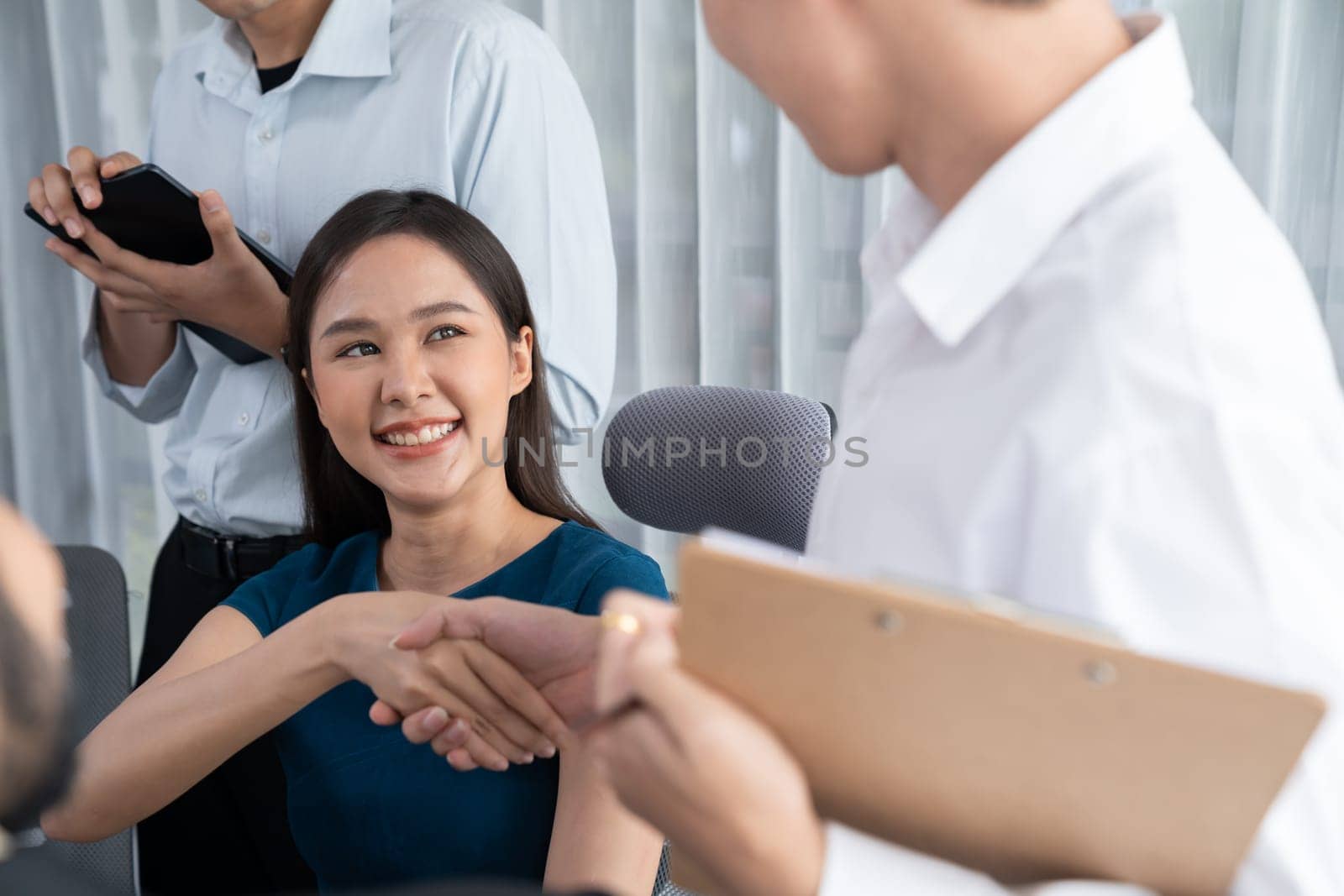 Diverse coworkers celebrate success with handshake and teamwork in corporate workplace. Multicultural team of happy professionals united in solidarity by handshaking in office. Concord