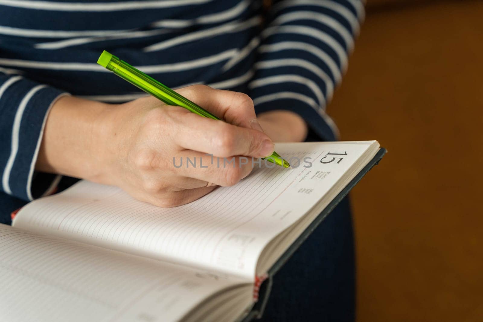 a woman makes notes in a notebook keeping important thoughts and moments on paper. A girl sitting on a yellow sofa fills out a diary, making plans for tomorrow