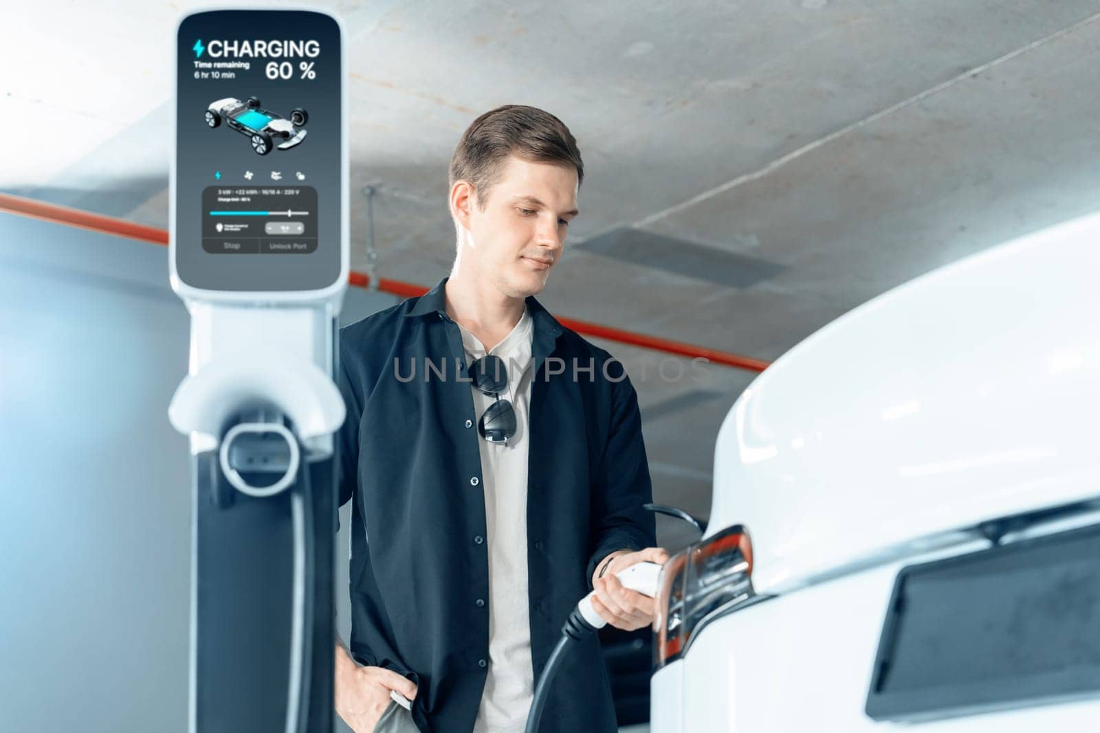 Young man travel with EV electric car to shopping center parking lot charging in downtown city showing urban sustainability lifestyle by green clean rechargeable energy of electric vehicle innards