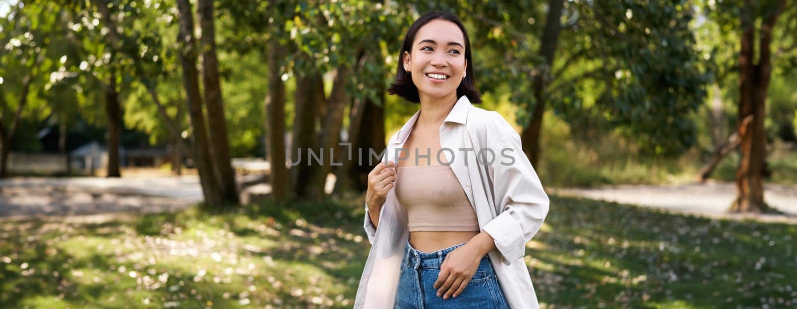 Stylish asian girl walks in park, laughs and enjoys summer weather. People and lifestyle concept.