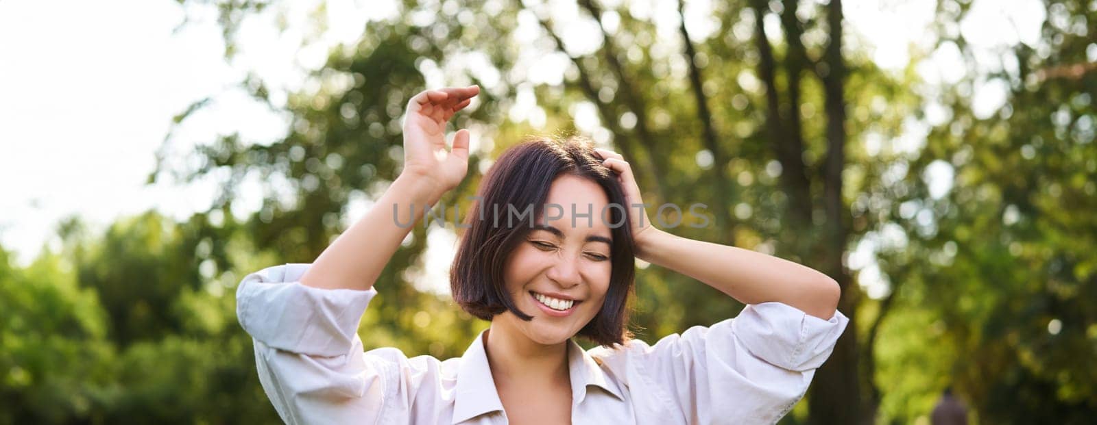 People and emotions concept. Happy asian woman laughing and smiling, posing on summer day in park by Benzoix