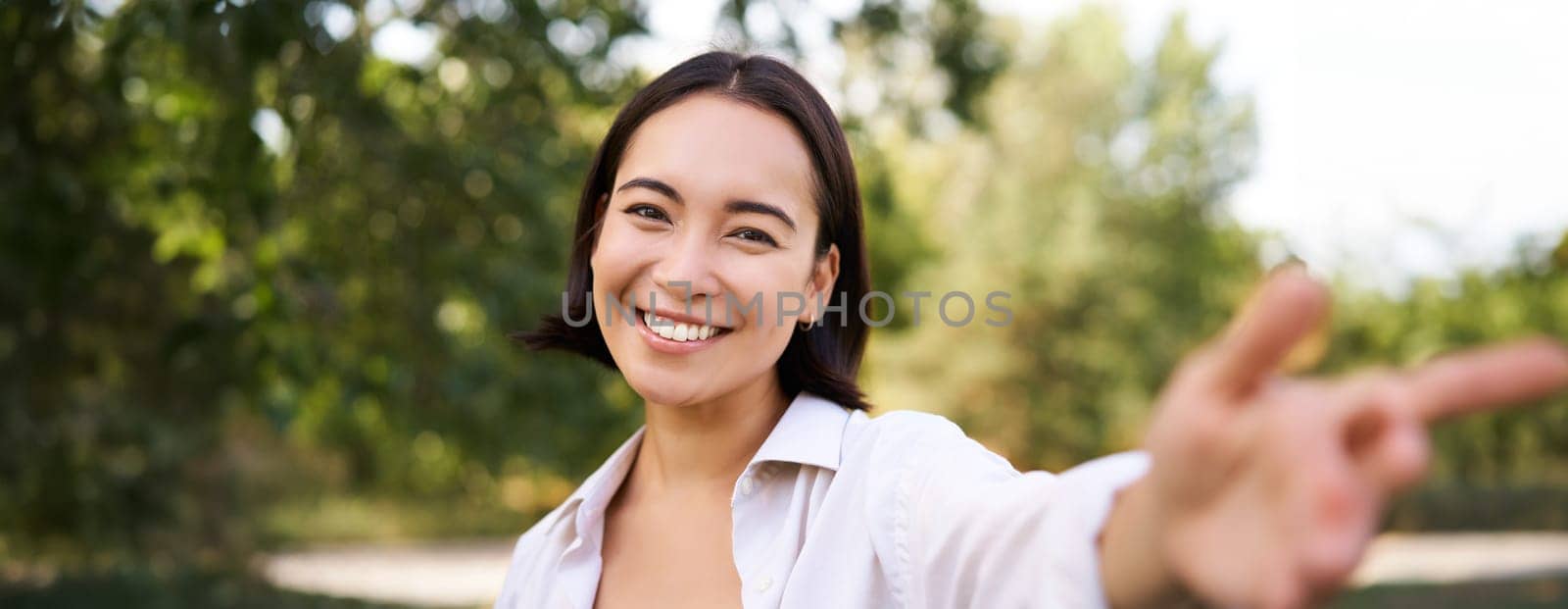 People and lifestyle. Happy asian woman takes selfie in park, photo on smartphone, smiling and looking joyful by Benzoix