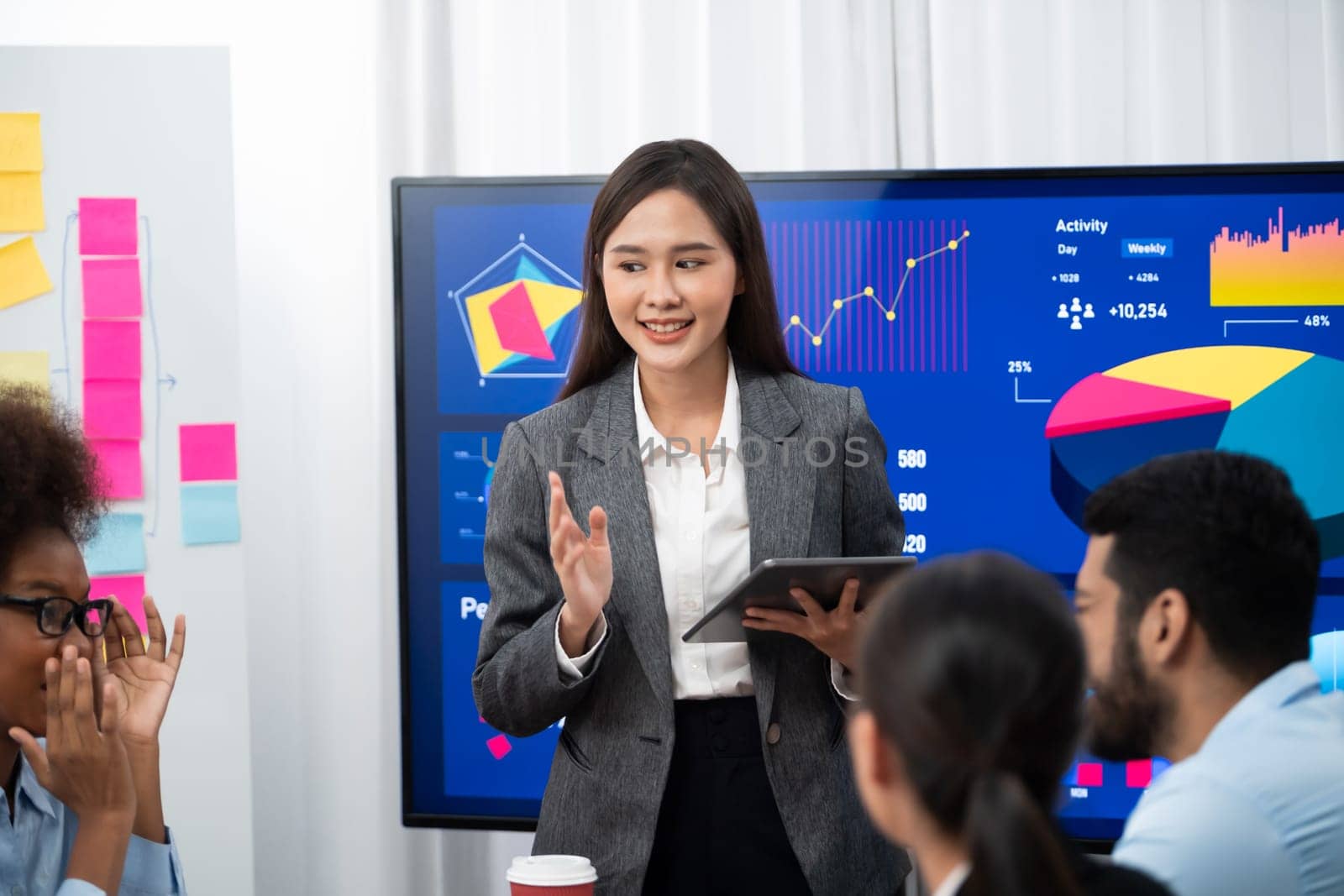 Young asian businesswoman presenting data analysis dashboard on TV screen in modern meeting. Business presentation with group of business people in conference room. Concord