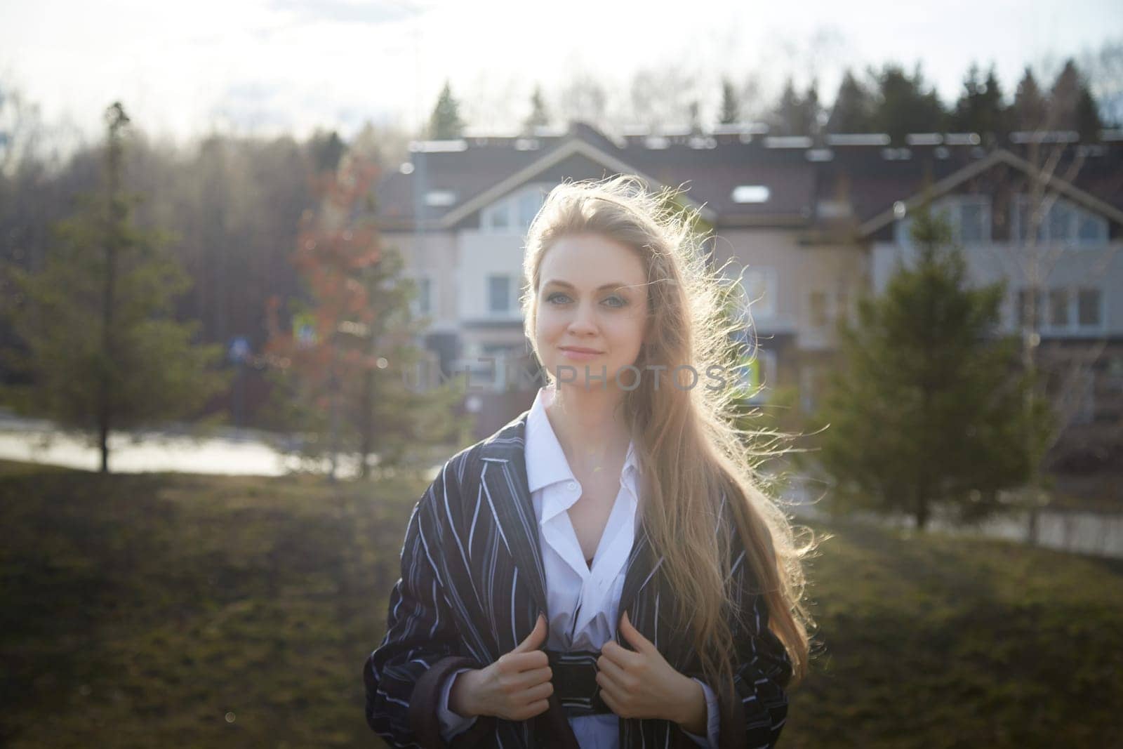 Portrait of Beautiful girl with long blonde hair in white shirt and jacket in village or small town. High young slender woman in an autumn, spring, summer day