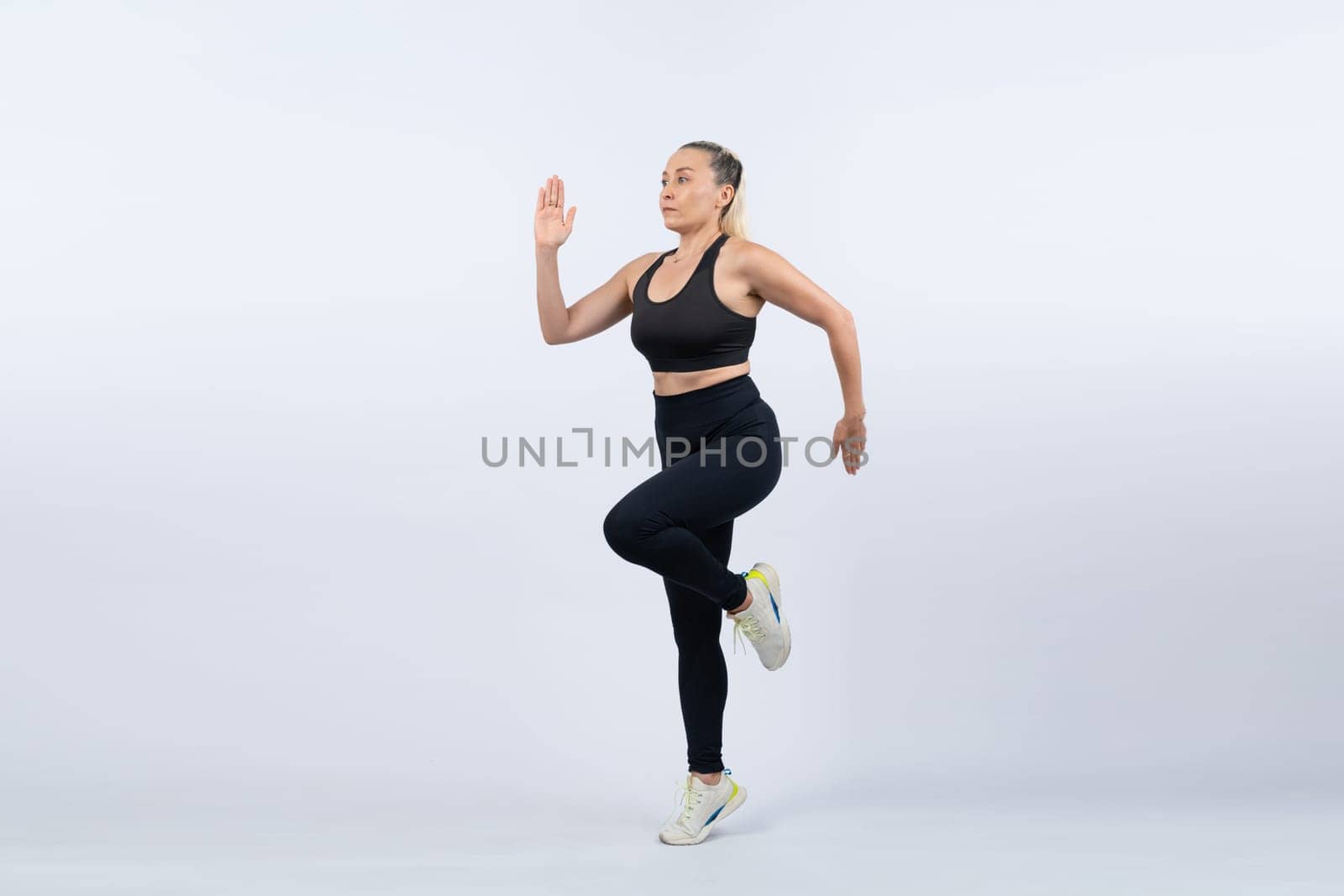 Active and fit physique senior woman in sportswear portrait in running posture isolated background. Healthy lifelong senior people with fitness healthy and sporty body care lifestyle concept. Clout