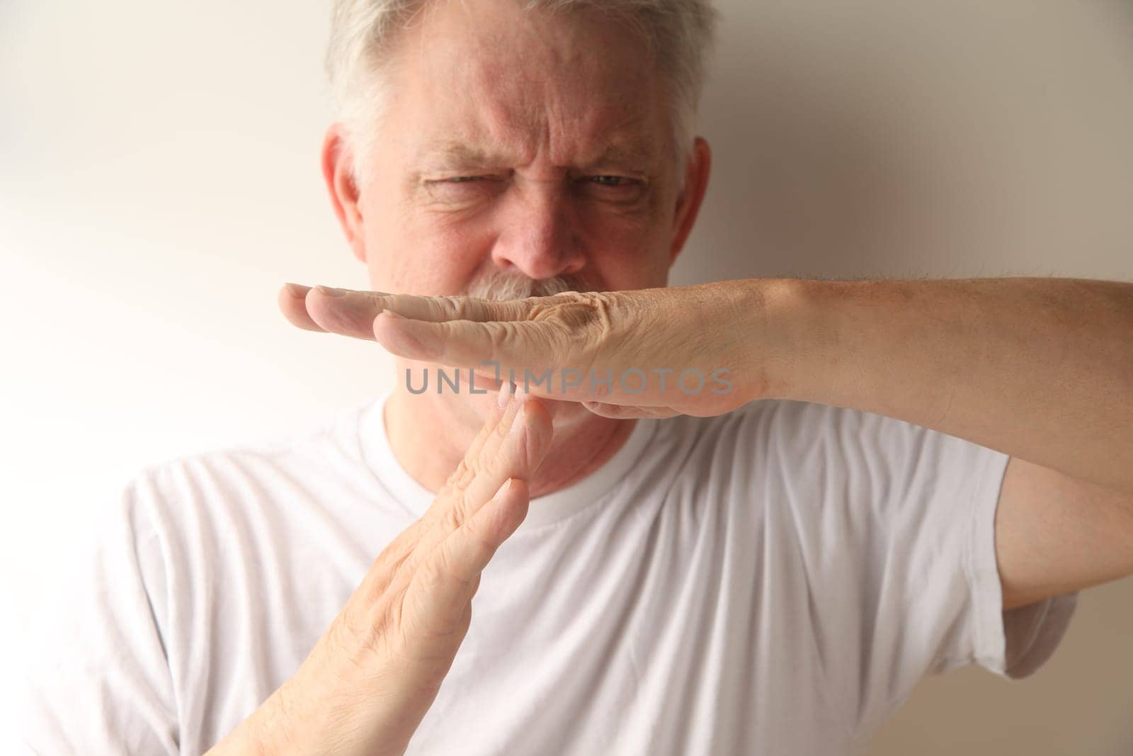 an older man gives the timeout gesture