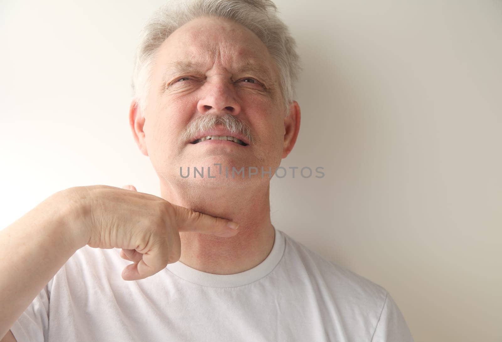 an older man gives the cutthroat signal