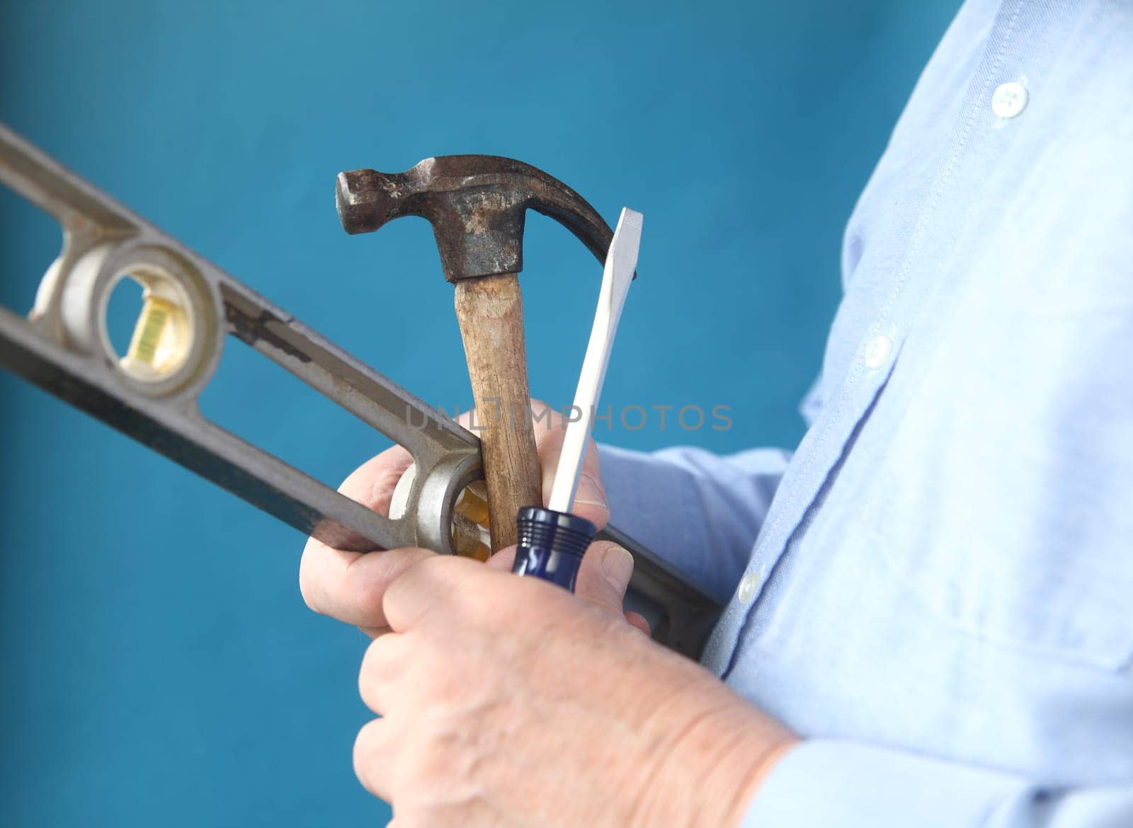 a man holds a hammer, screwdriver and level