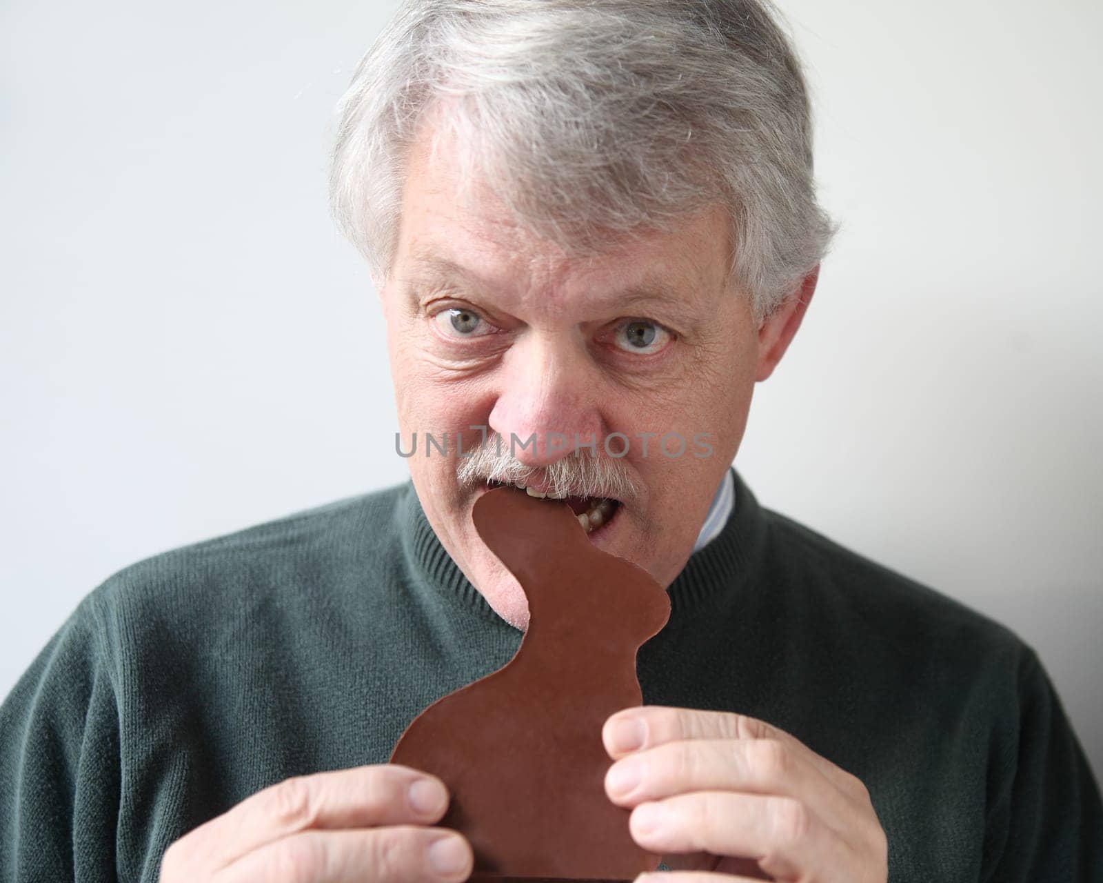 senior man bites into chocolate rabbit