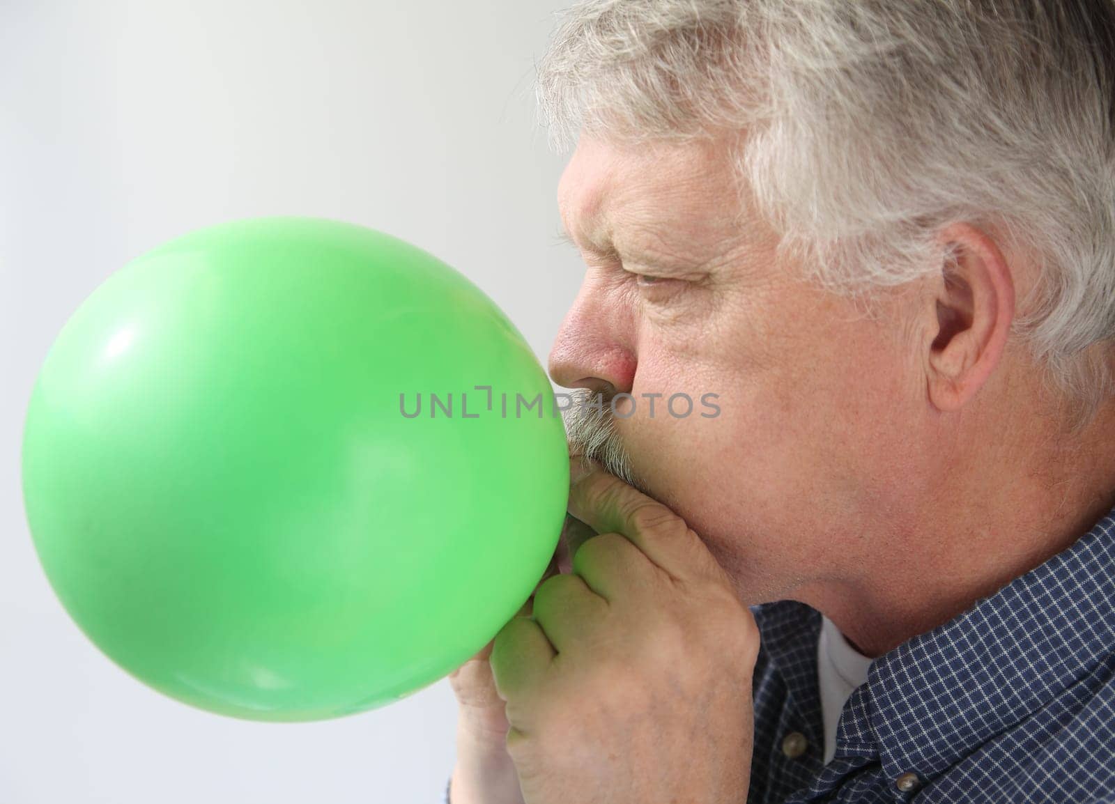 a man blows up a green balloon