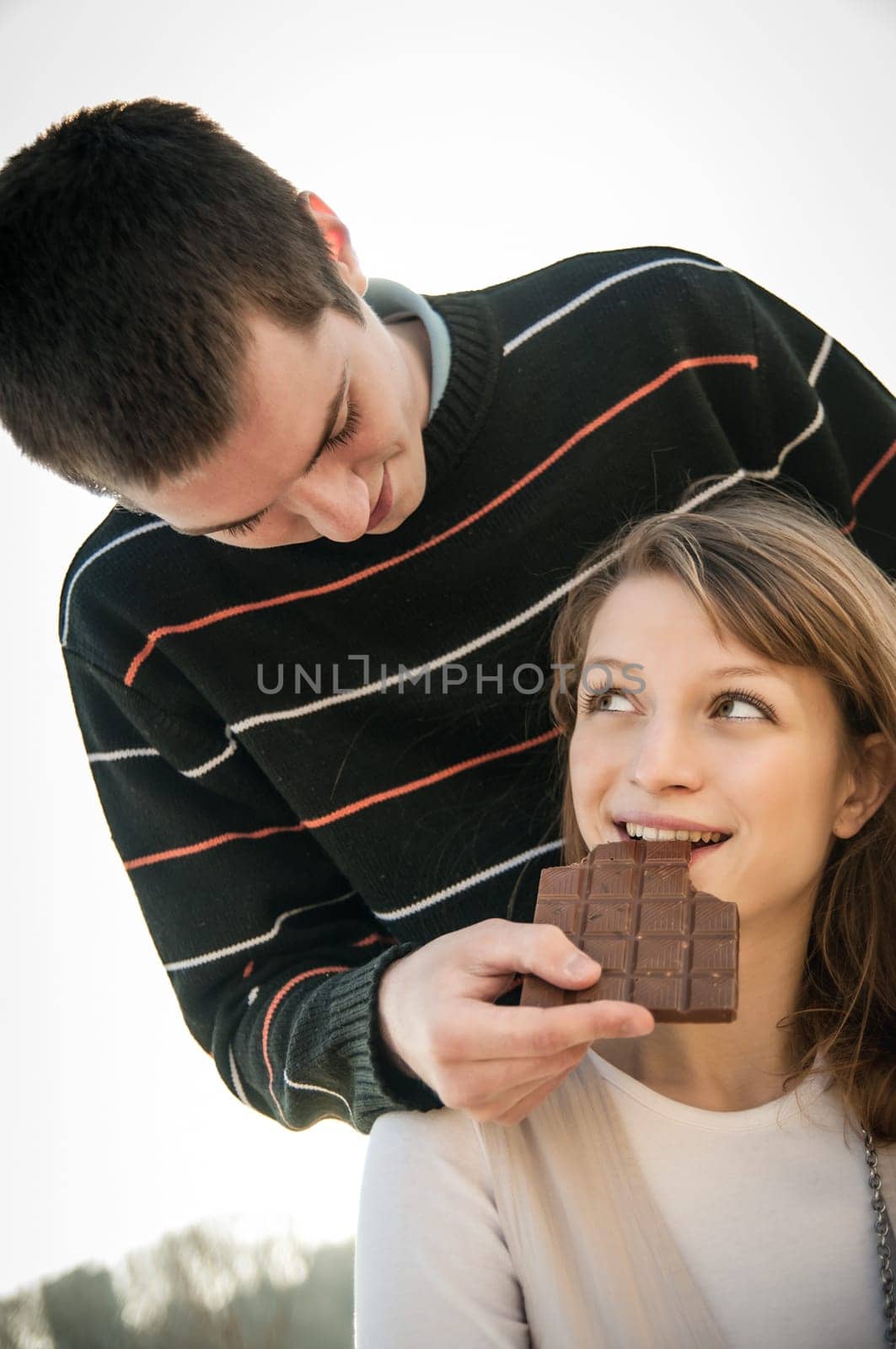 Young happy couple together outdoor - man gives chcolate to woman