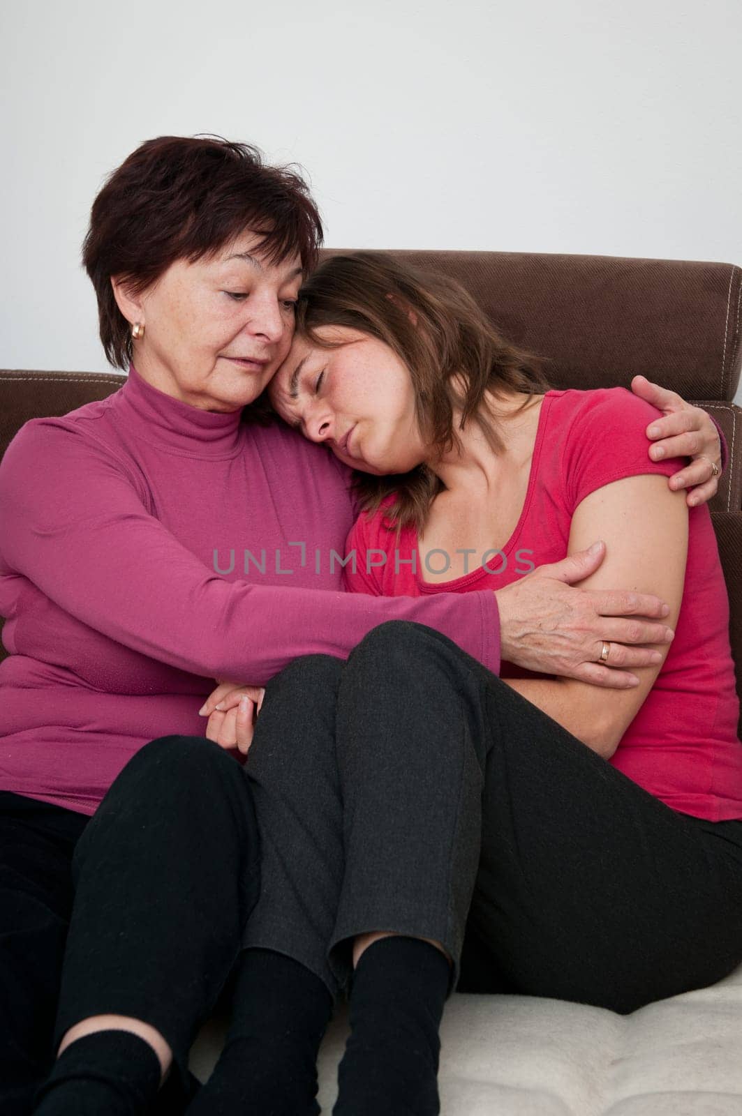 Mother senior woman) comforts her depressed aduld daughter at home