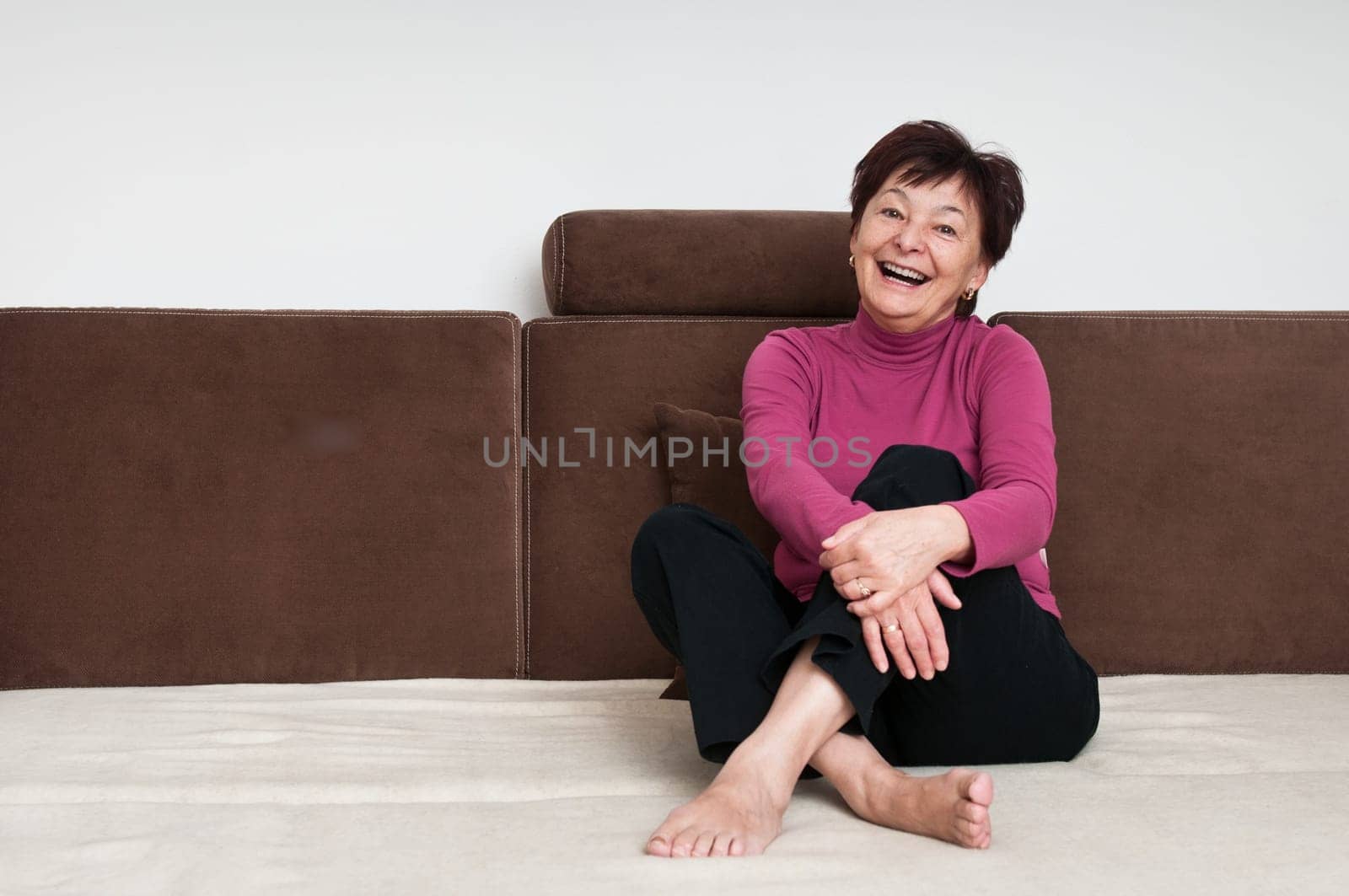 Portrait of smiling senior woman sitting on sofa at home