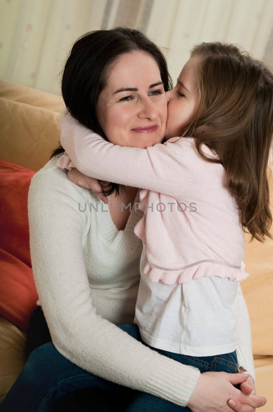Child (cute ligirl) kissing her mother - indoors at home
